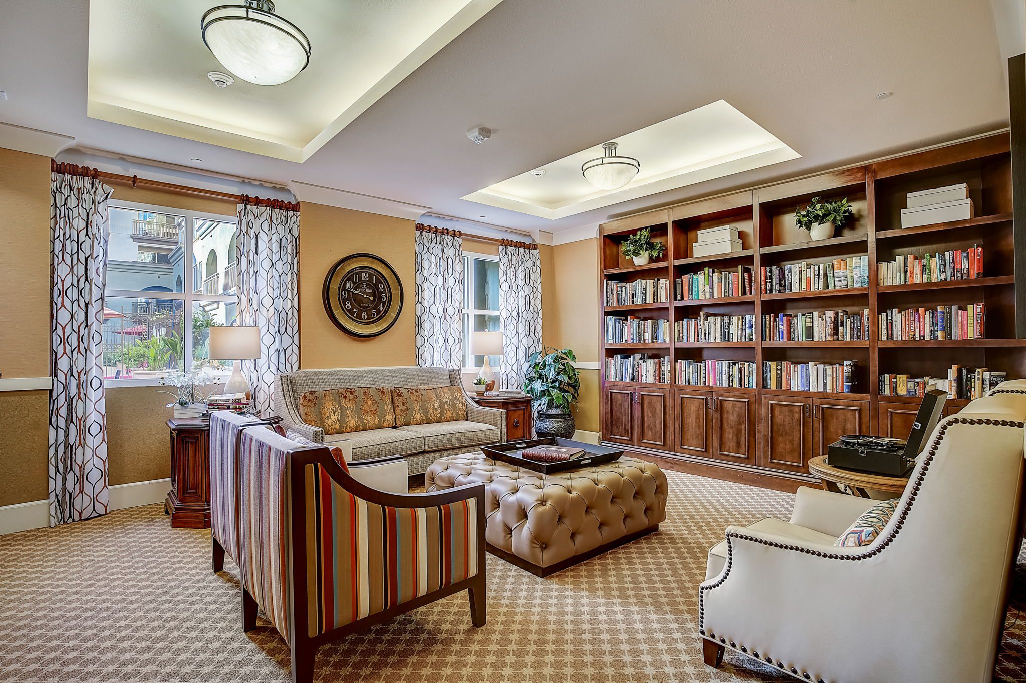 A cozy living room with a spacious bookcase filled with books and comfortable chairs for relaxation.