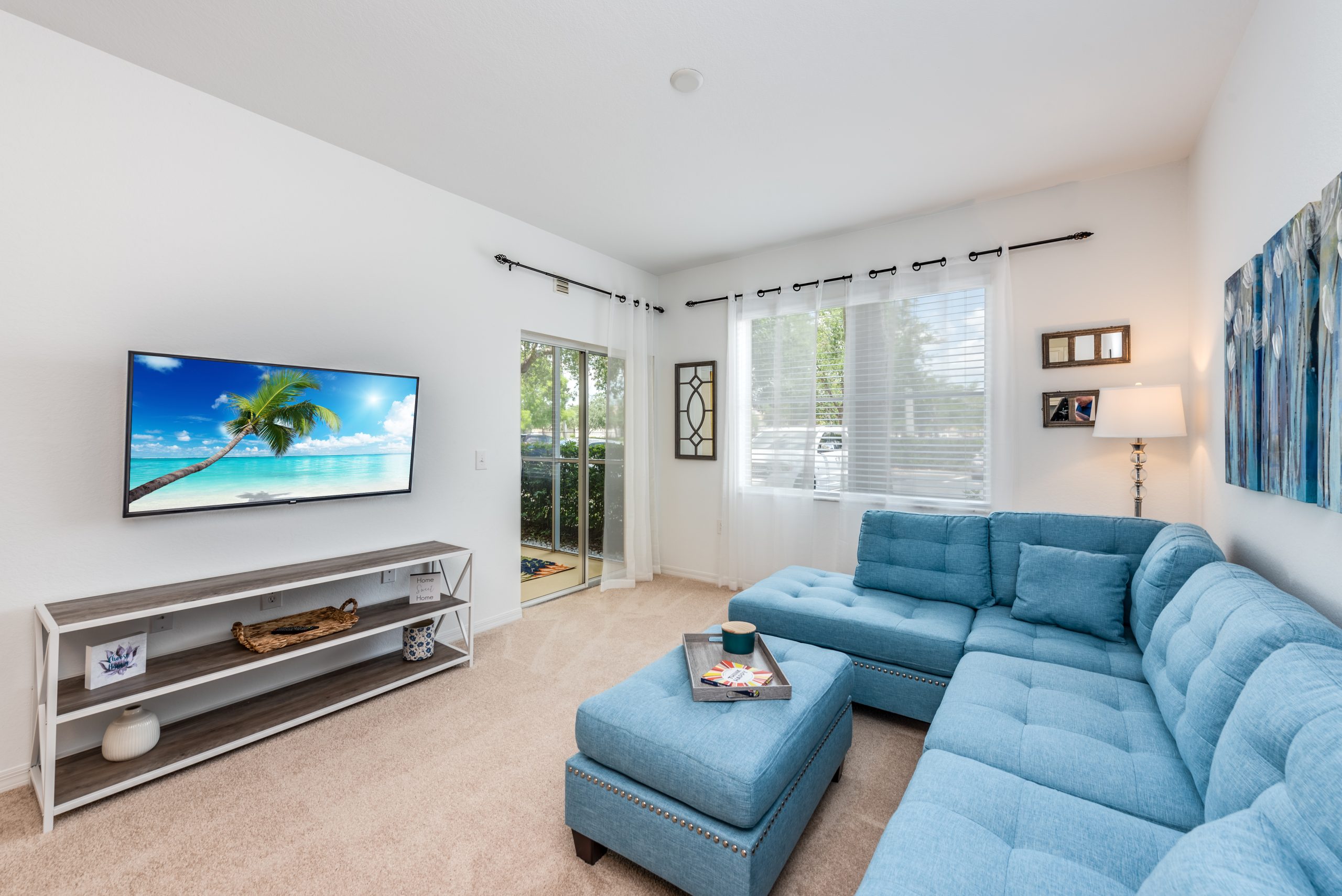 A modern living room with stylish blue couches and a large flat screen TV.