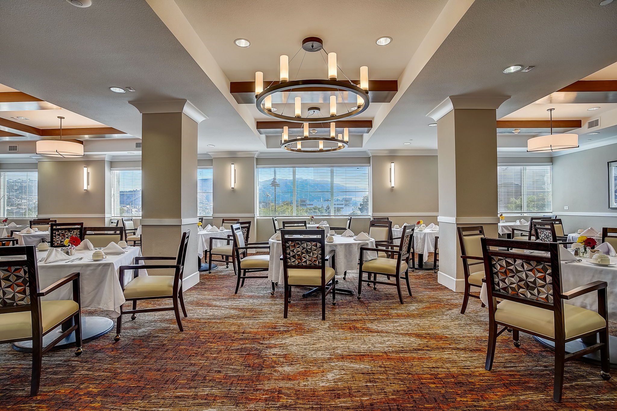 Elegant dining room in senior living community, featuring cozy tables, stylish decor, and warm lighting.