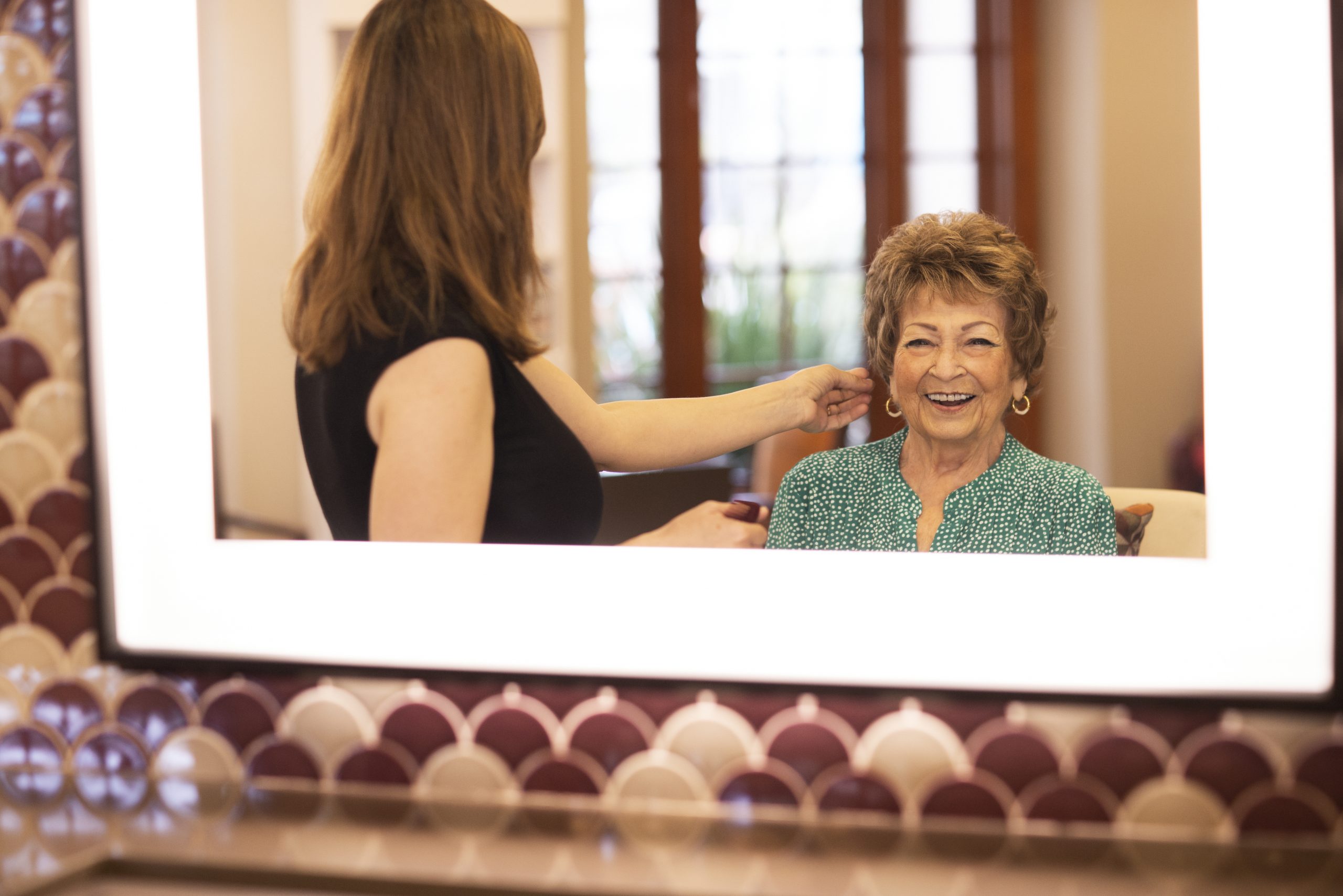 an elderly woman getting her hair done and looking in the mirror