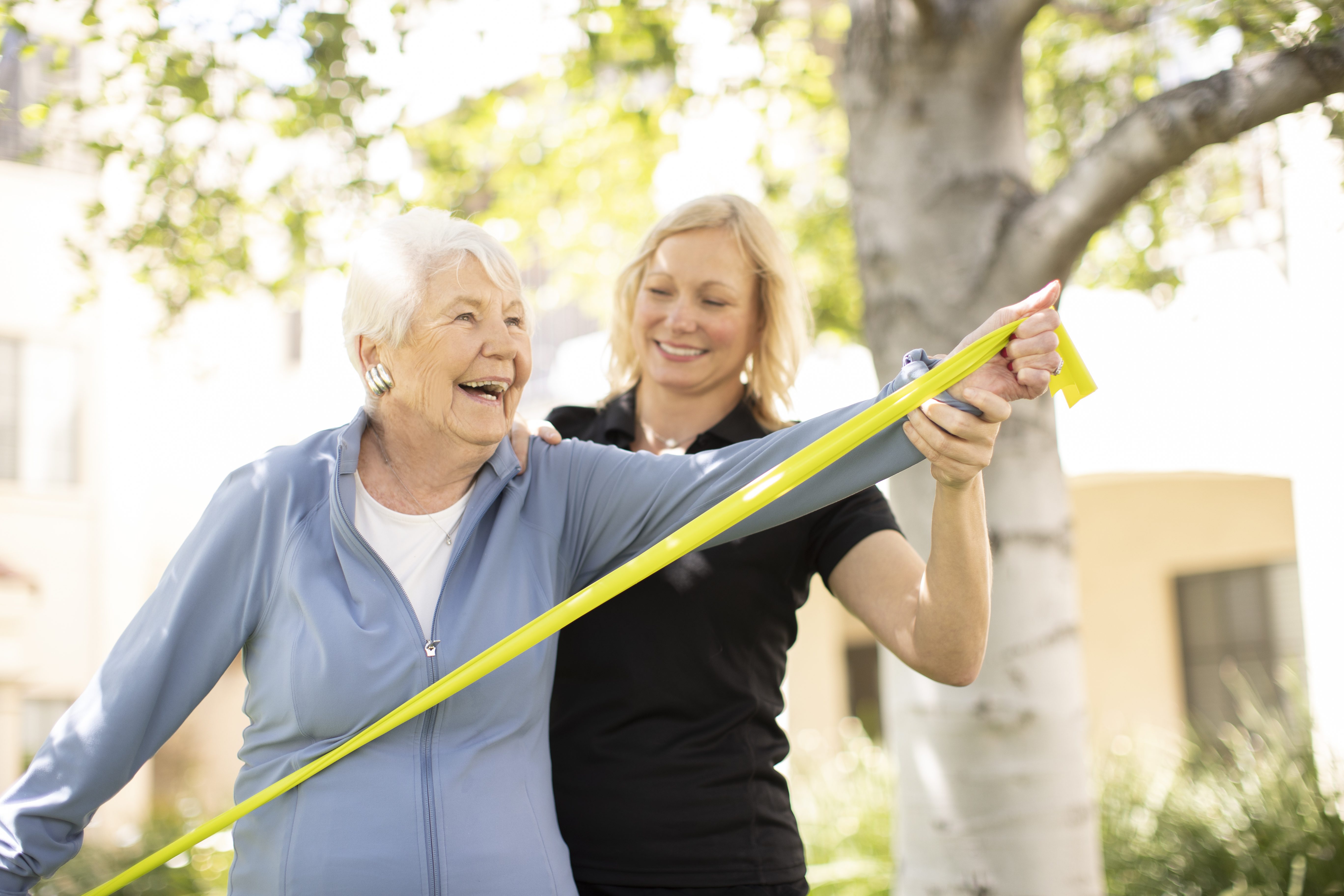 an elderly woman being assisted by a fitness coach on her exercise