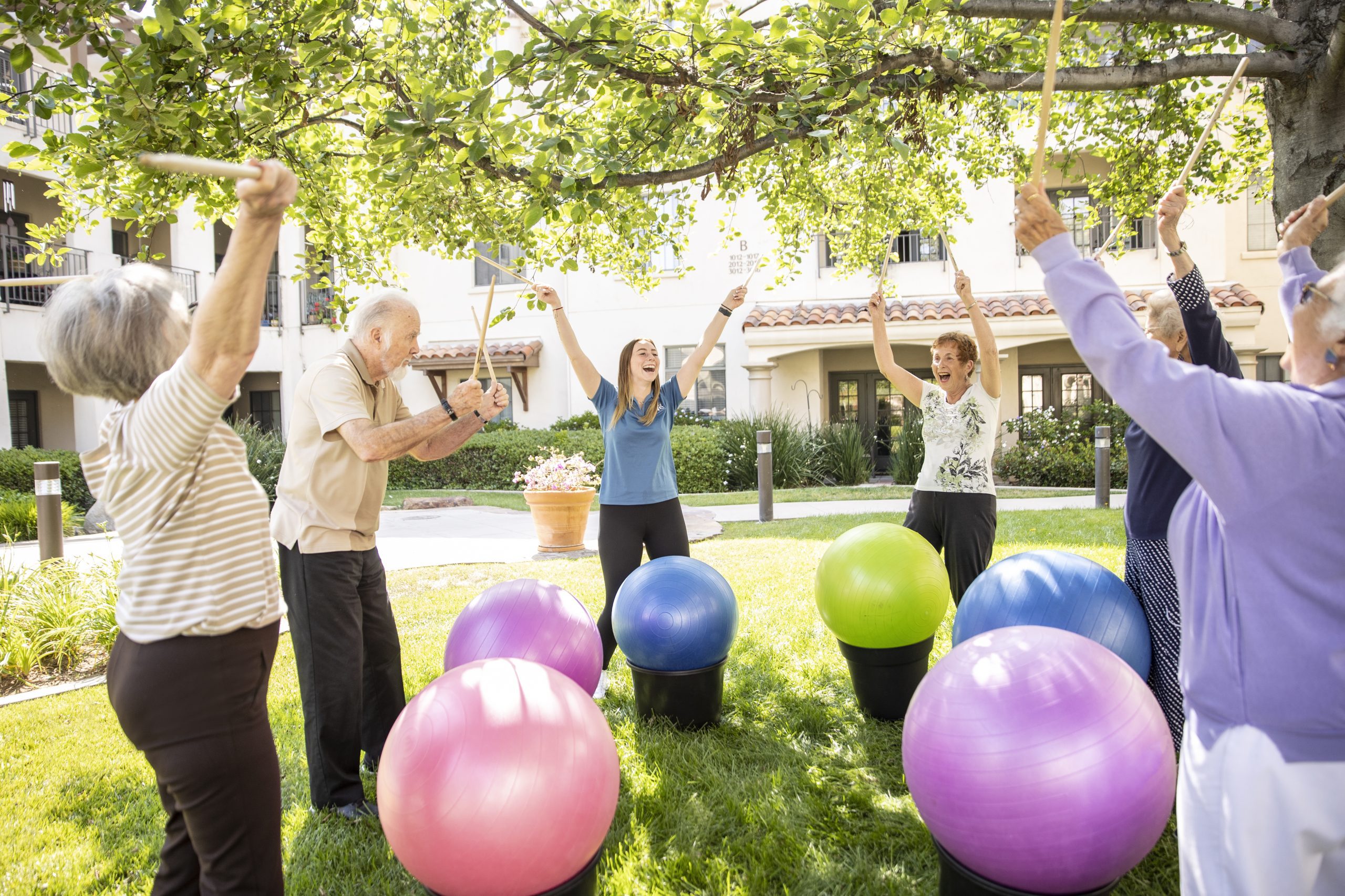 Senior adults exercising with colorful balls in the park, promoting physical fitness and social interaction.