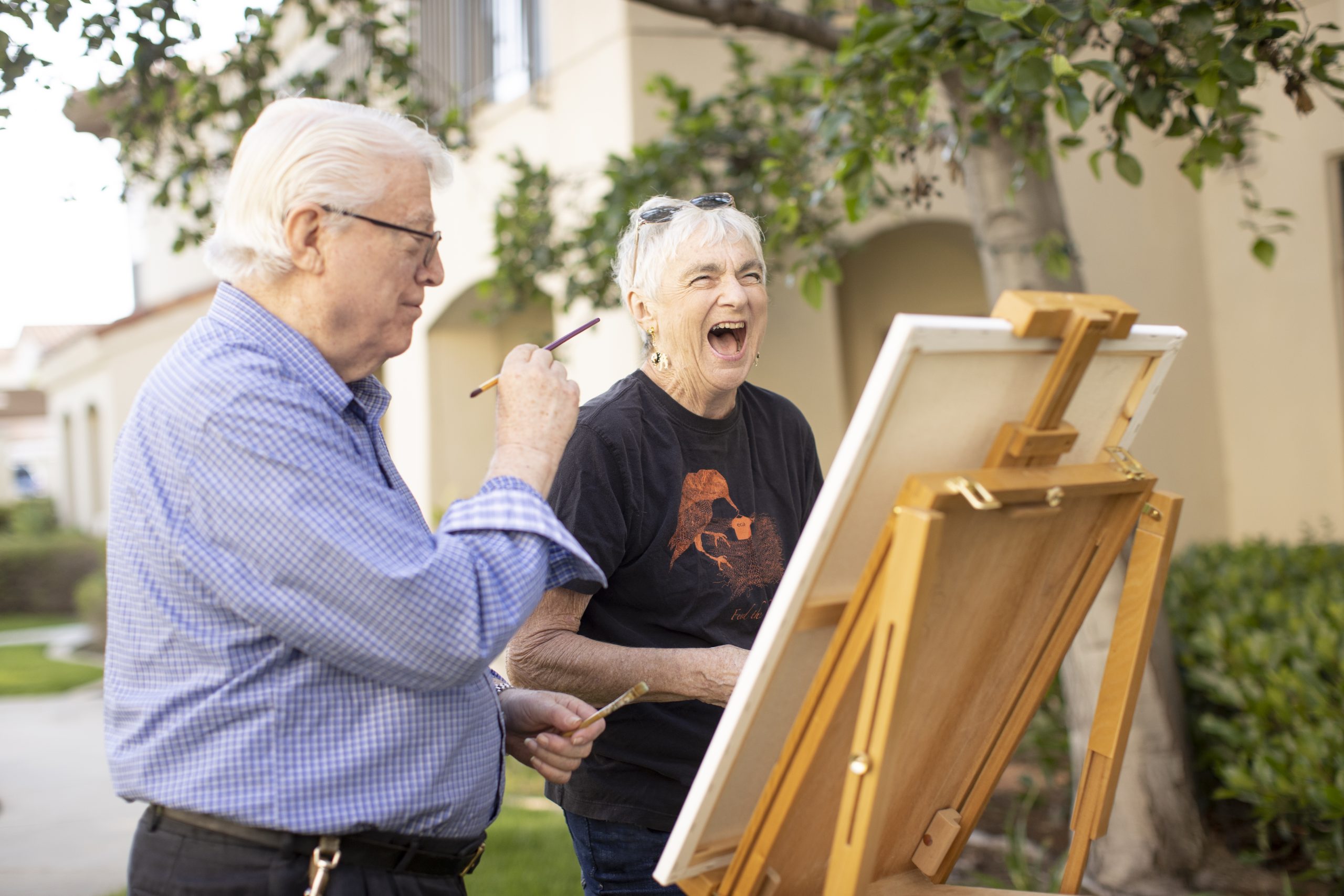 An elderly couple enjoying a creative moment as they paint together outdoors.