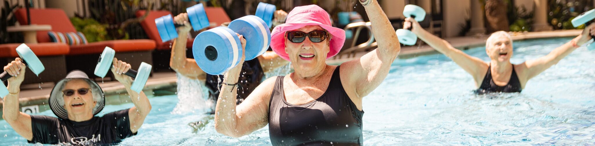 Smiling senior women participating in water aerobics in an outdoor swimming pool 