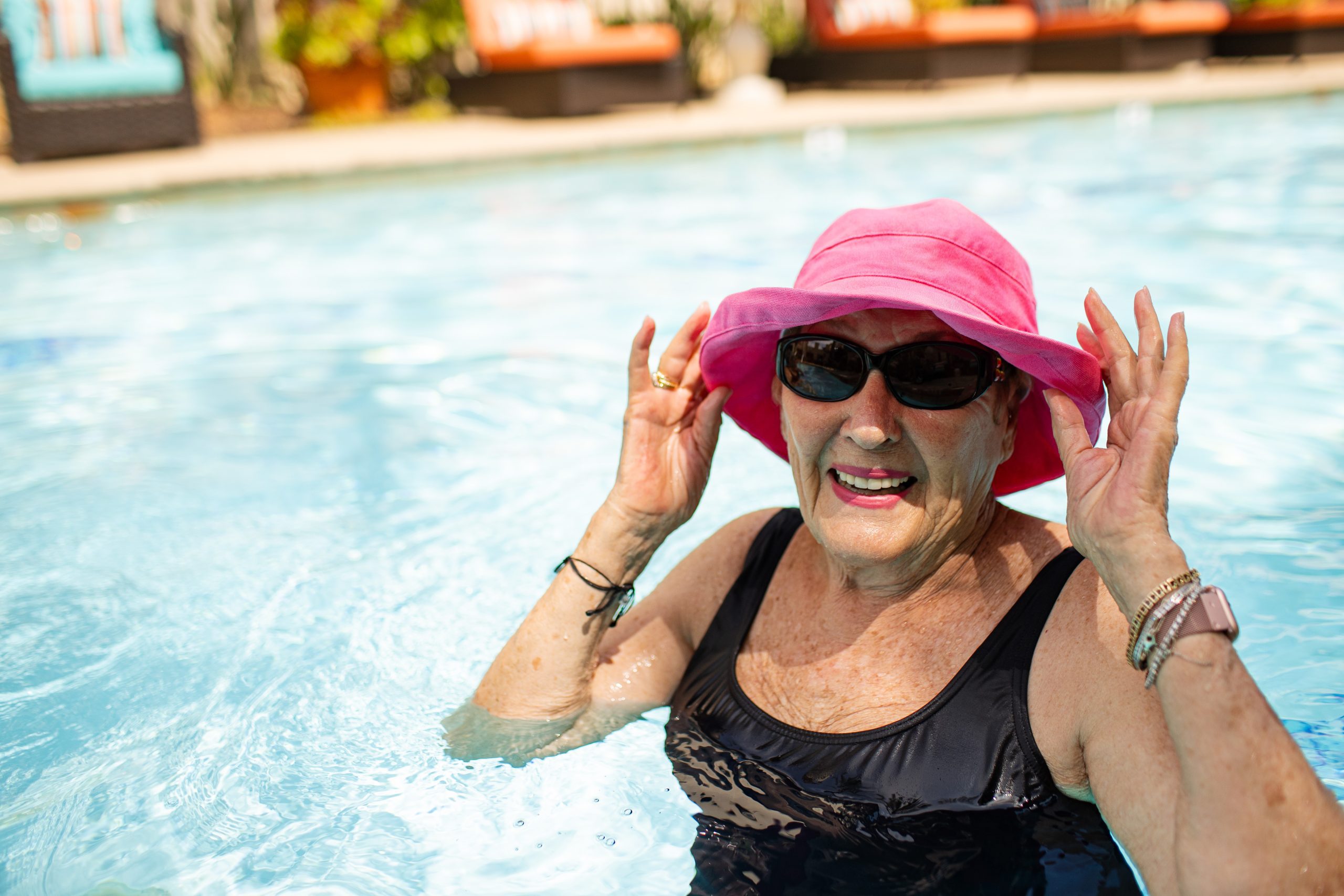 woman swimming in pool with hat and sunglasses