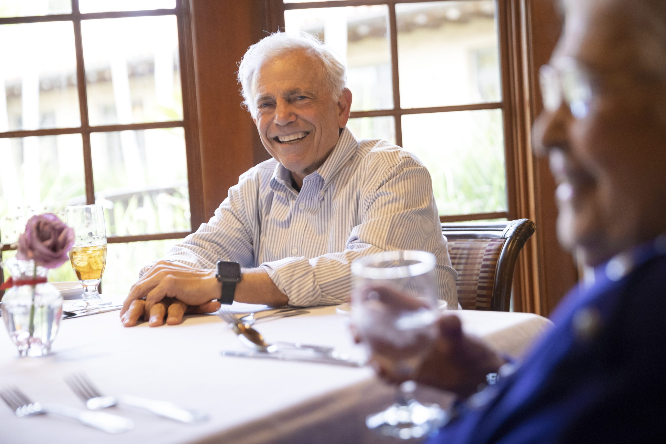 An elderly couple seated at a table, engaged in conversation and enjoying each other's company.