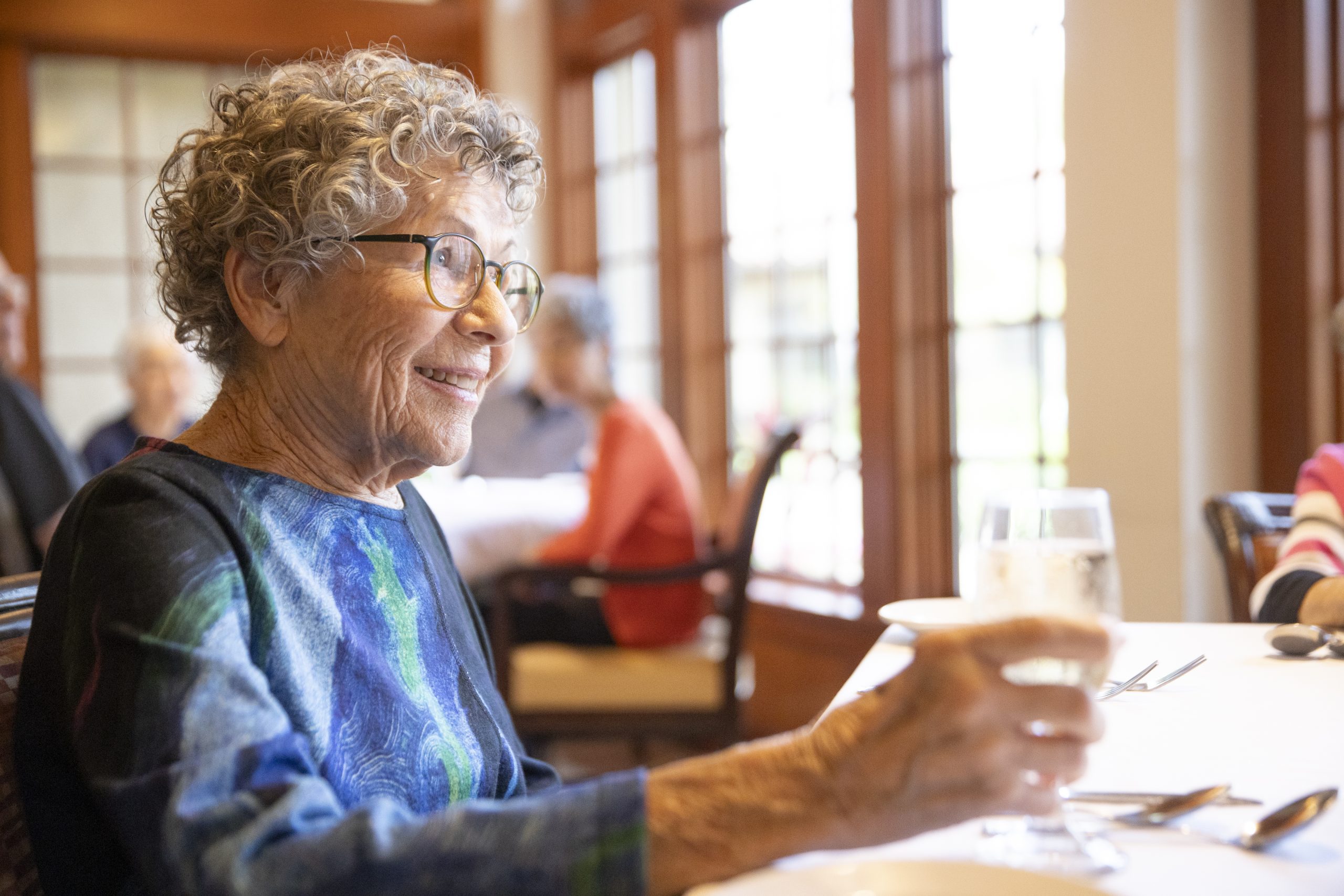 Elderly woman drinking wine and eating with her friends