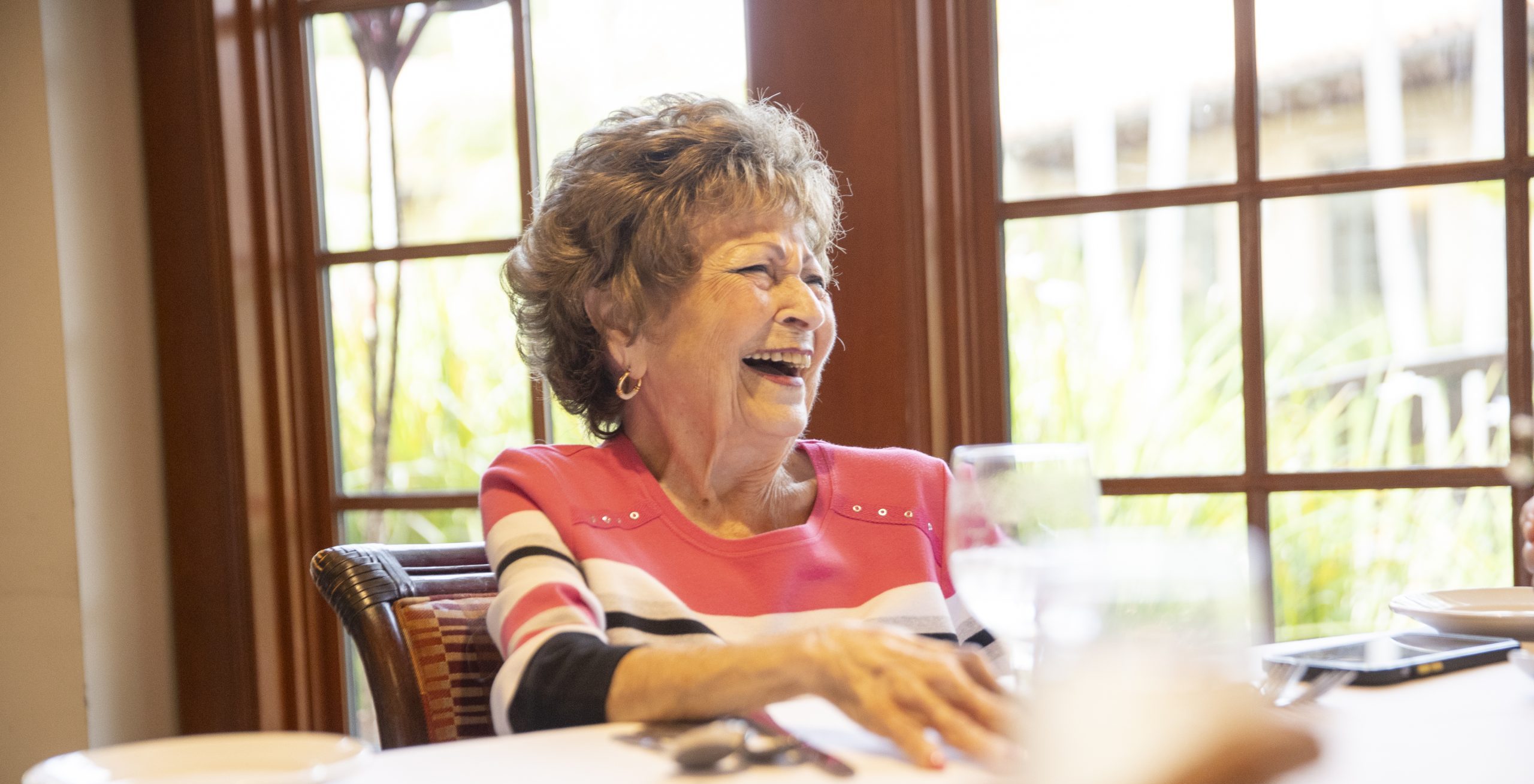 elderly woman laughing while dining with friends