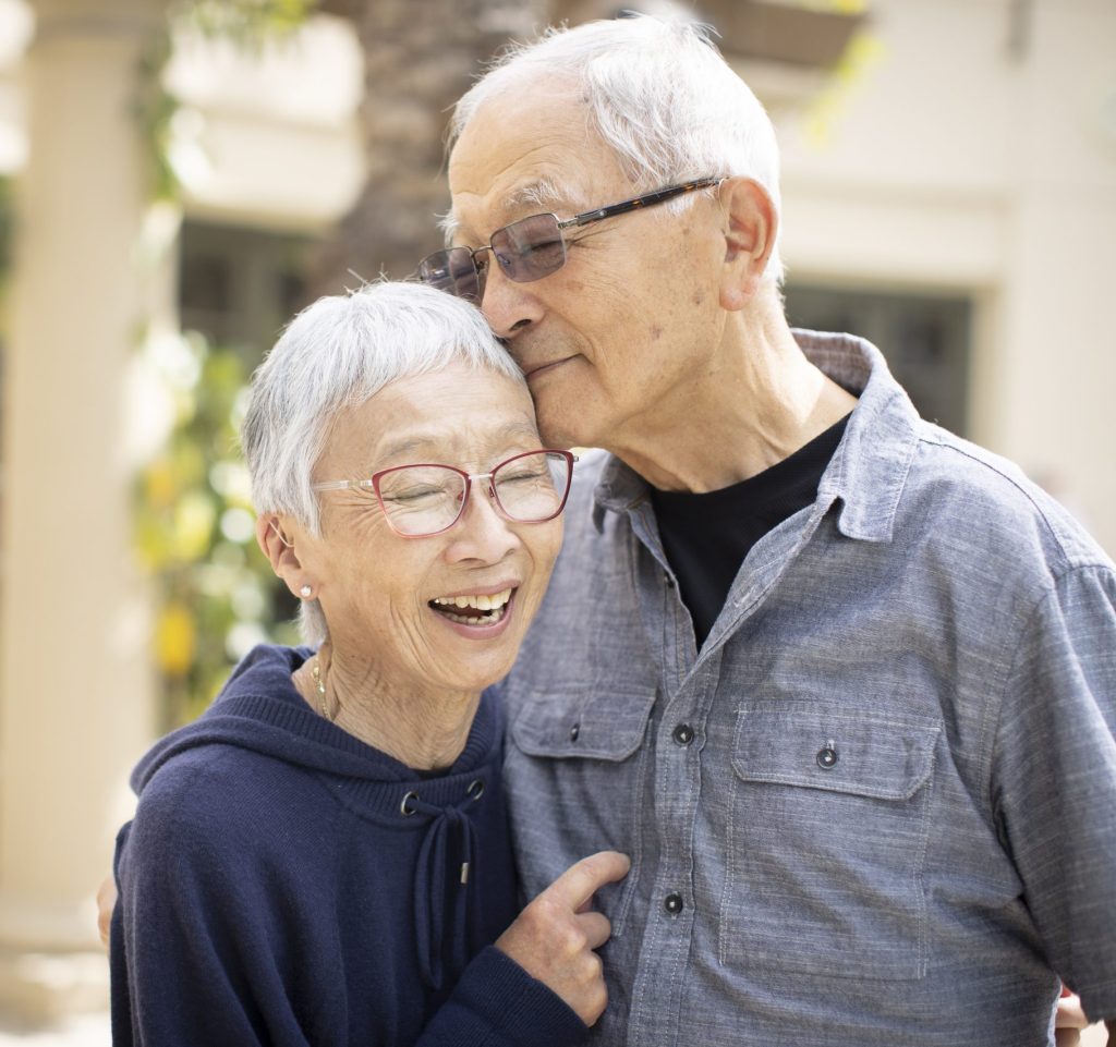 An older couple embraces, their faces beaming with joy, as they share a warm and affectionate hug.