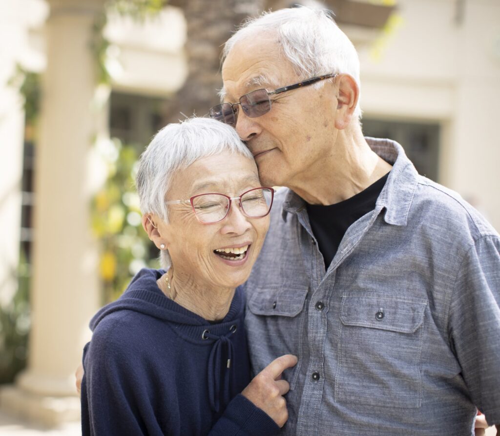 An older couple embraces, their faces beaming with joy, as they share a warm and affectionate hug.