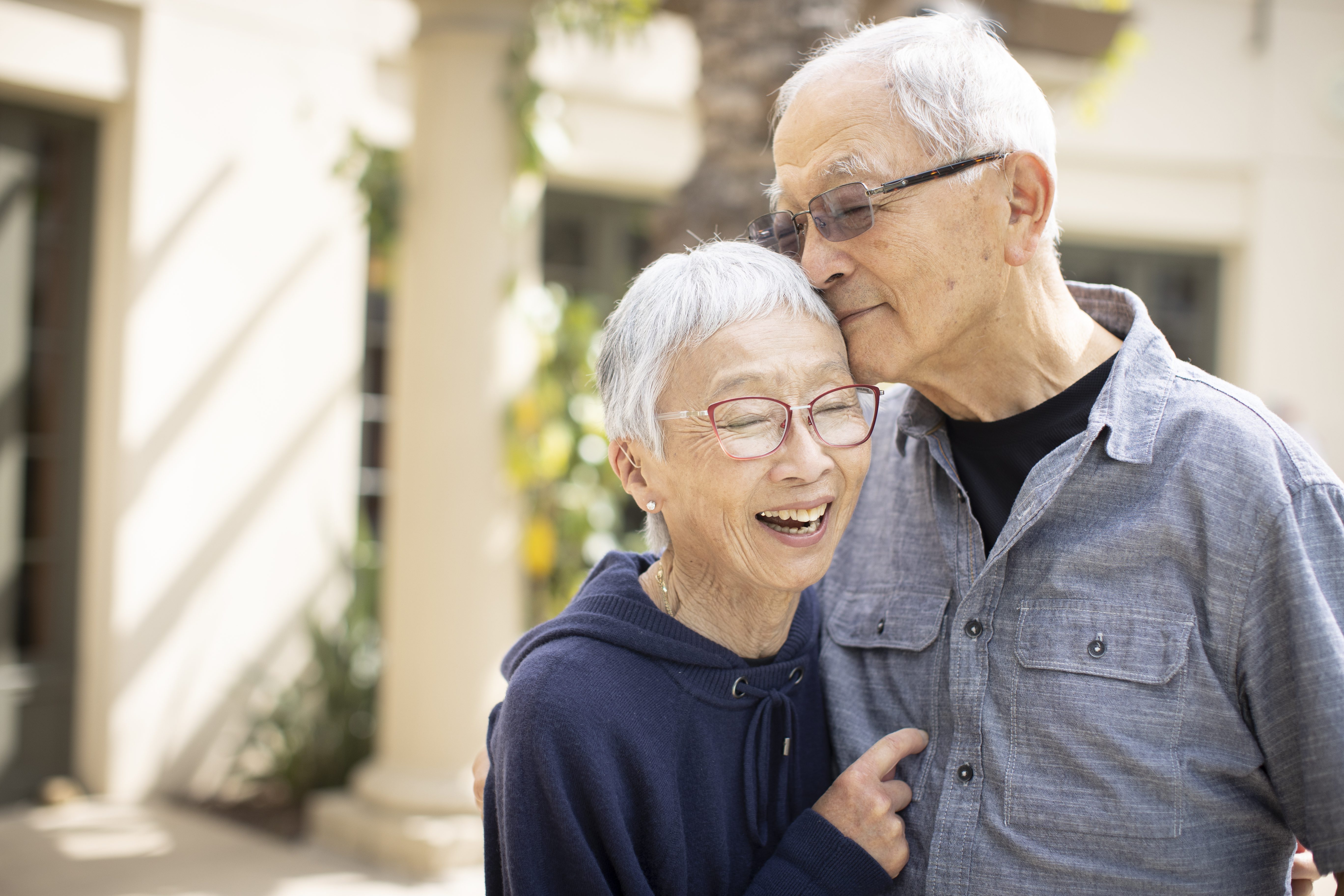 An older couple embraces, their faces beaming with joy, as they share a warm and affectionate hug.