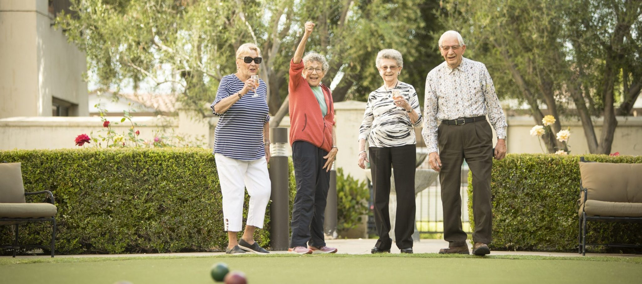 four active elderly people excited and playing croquet
