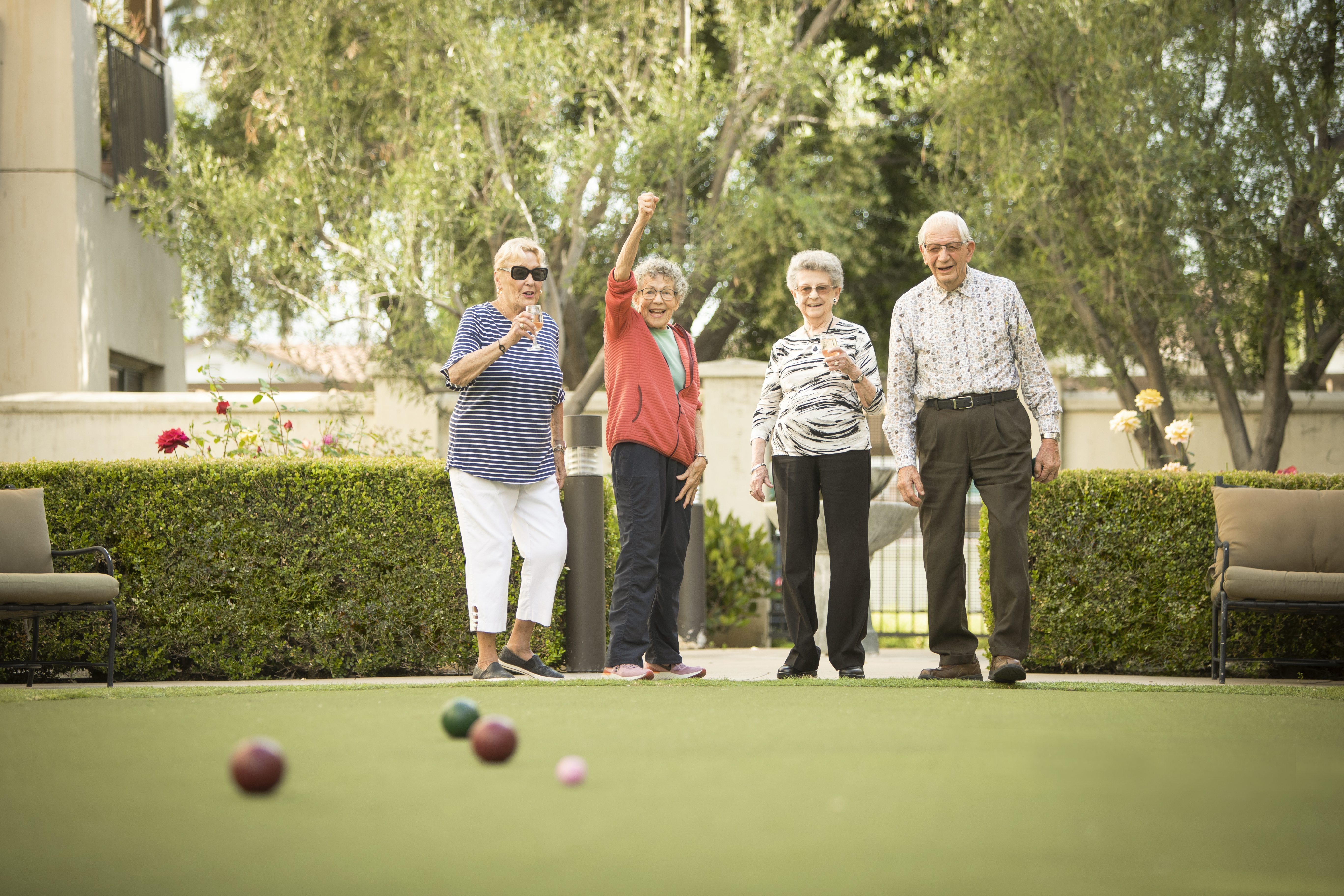 four active elderly people excited and playing croquet