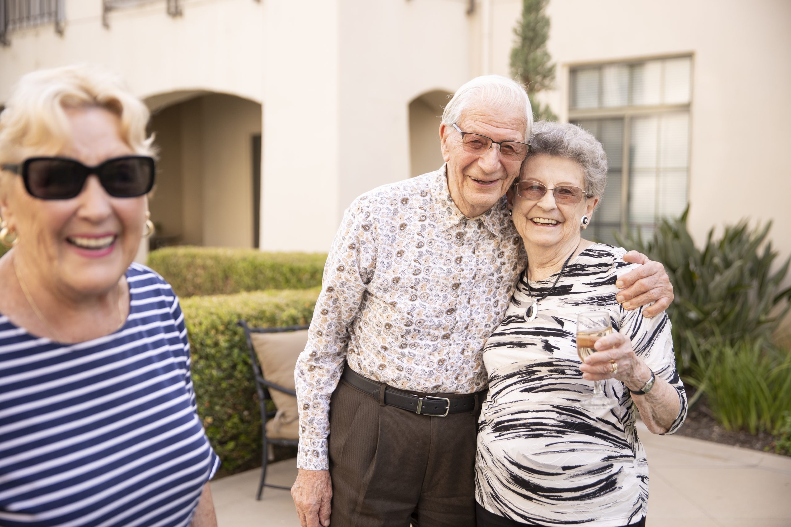 2 elderly friends hugging a few feet away from their other friend