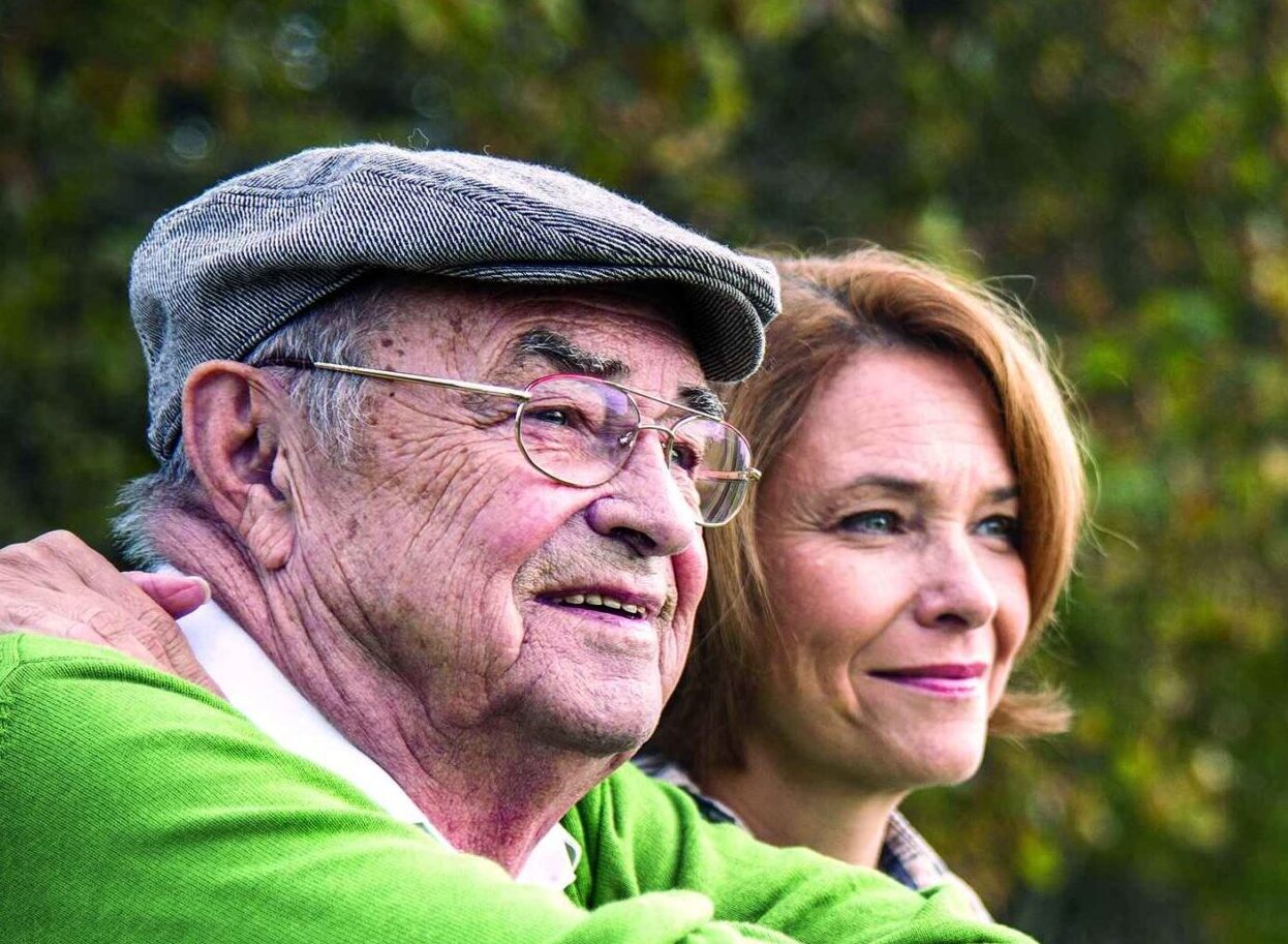 A senior man and his daughter sitting on a bench, smiling and enjoying each other's company in the USA