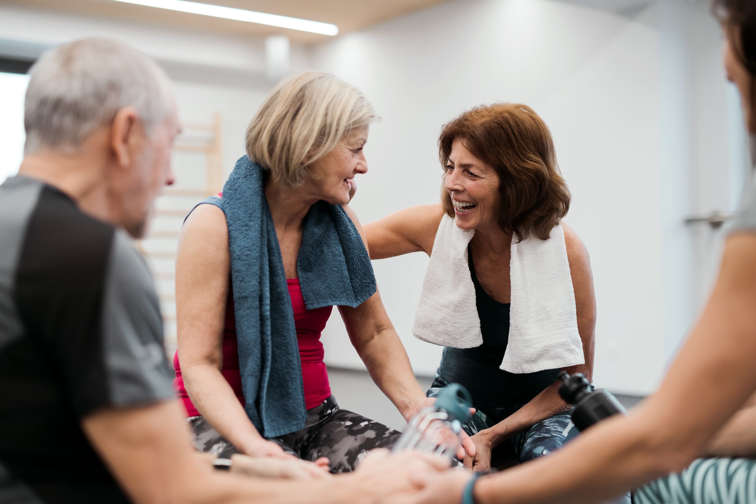 A joyful group of people in a gym, sharing laughter and smiles while engaging in physical activities.