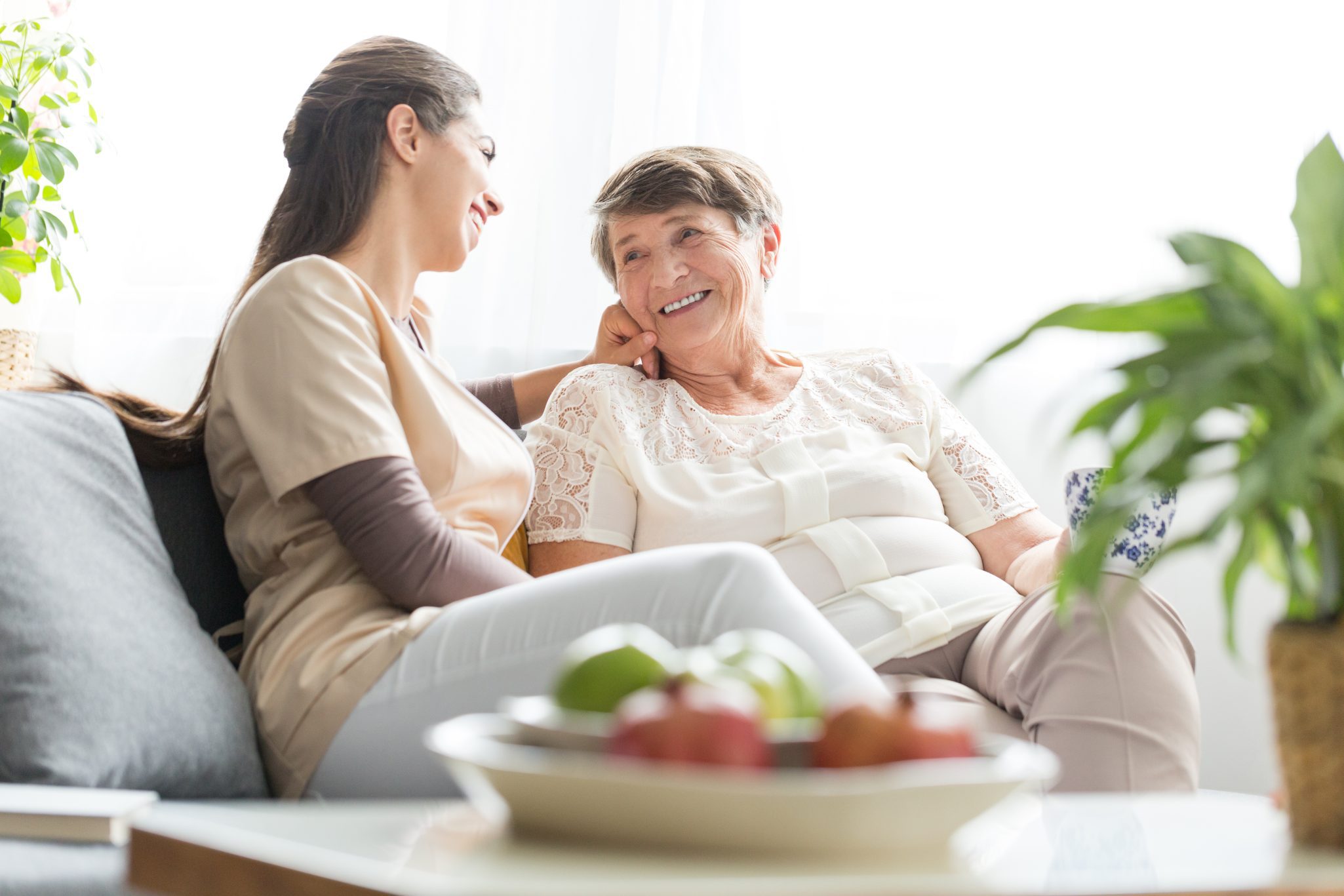 caregiver and elderly woman talking and smiling at each other