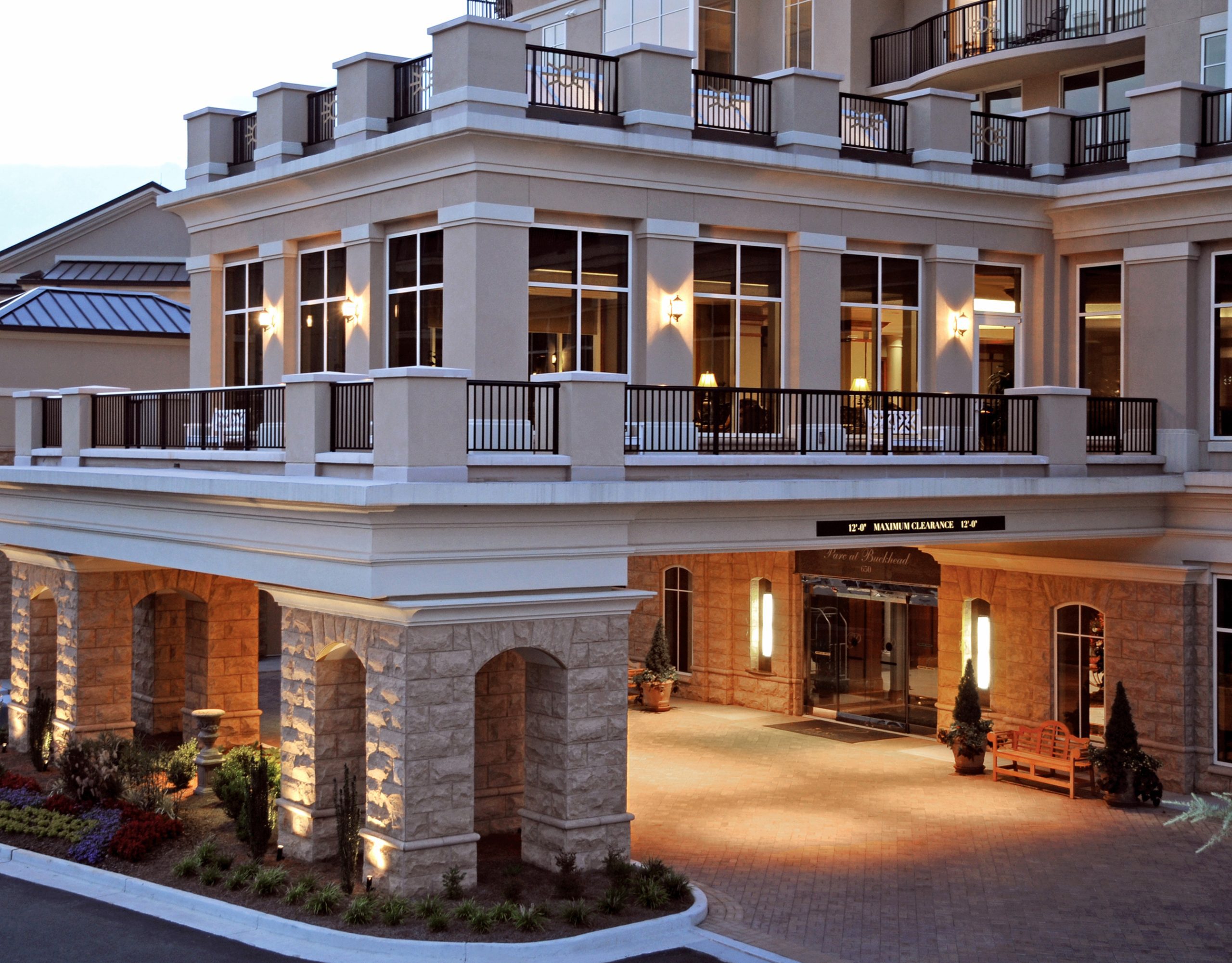 Front entrance of Piedmont Buckhead at night: illuminated entrance with glass doors, a doorman, and a sign displaying the hotel's name.