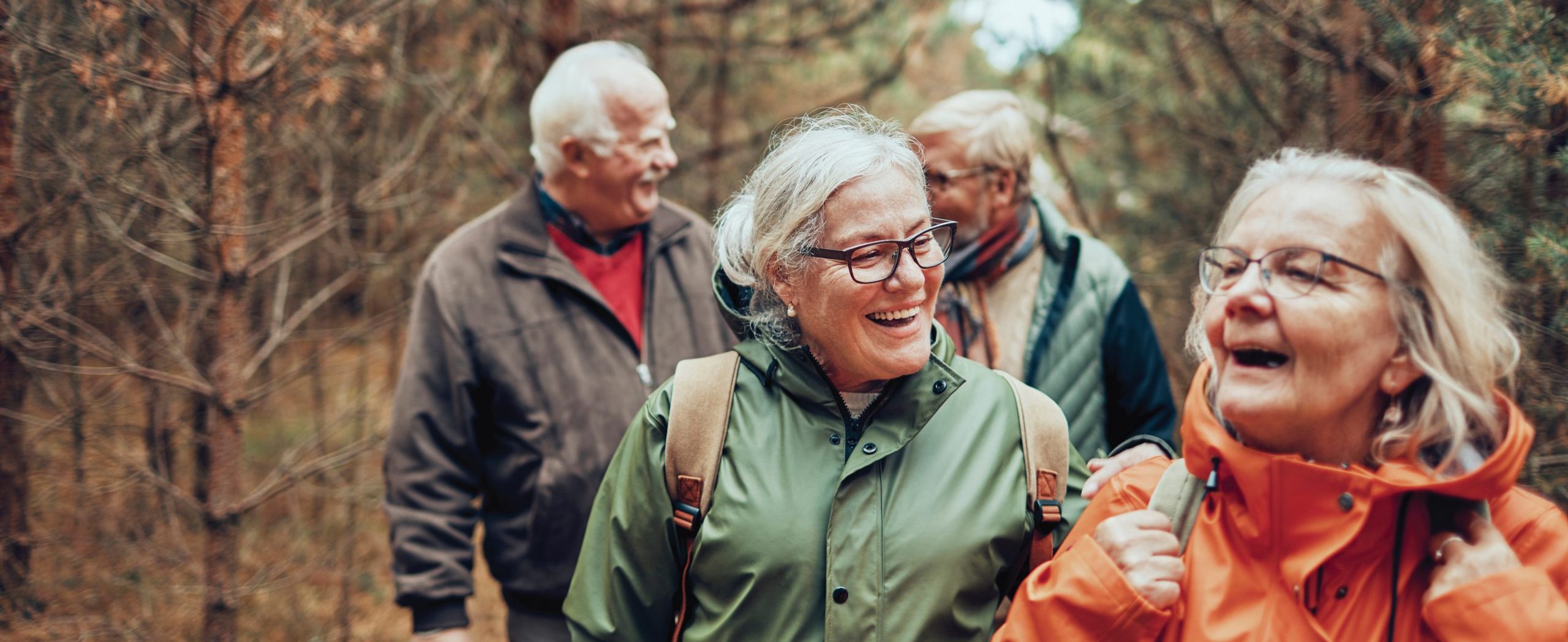 a group of elderly friends hiking in nature together wearing winter coats