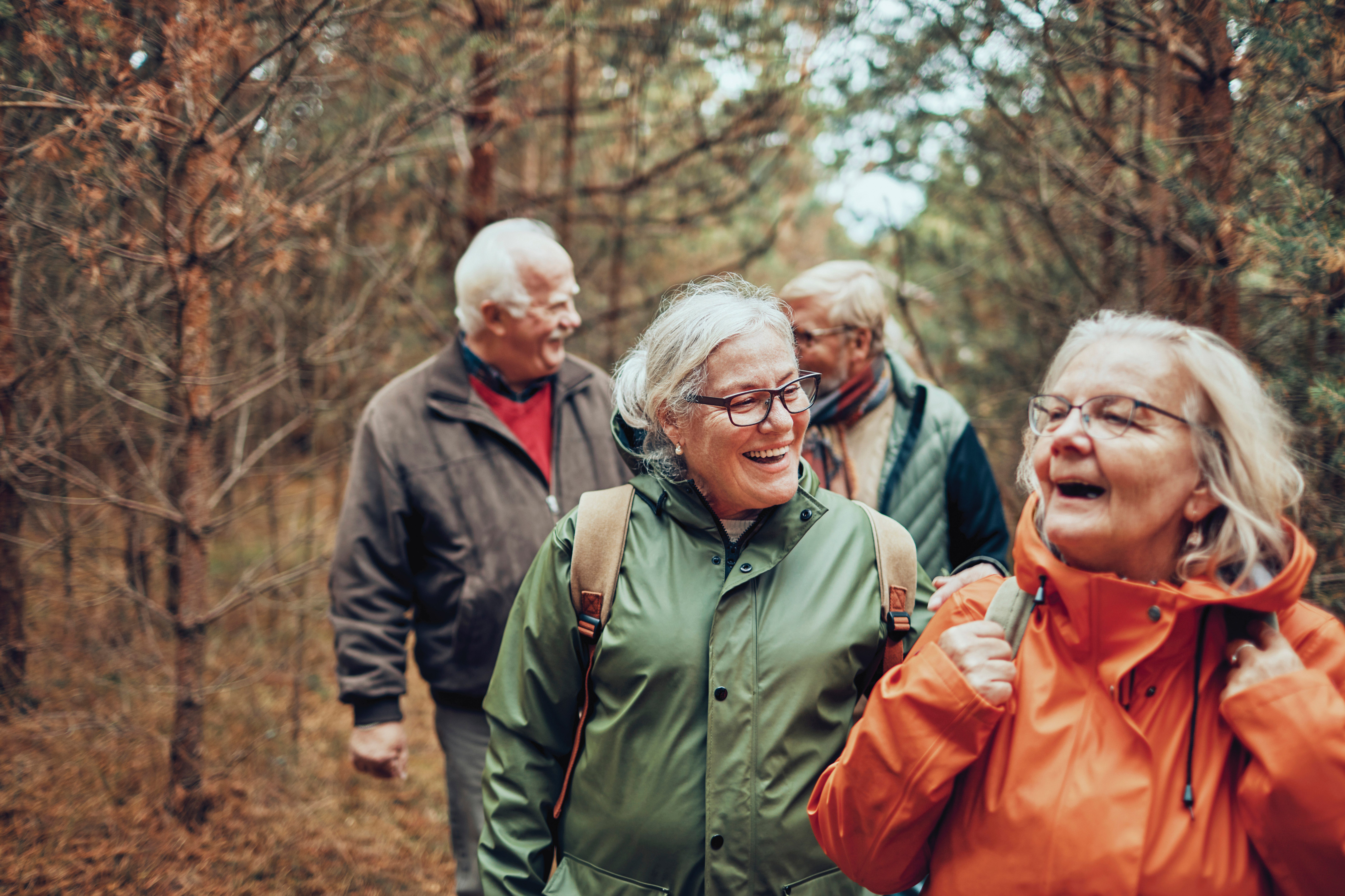a group of elderly friends hiking in nature together wearing winter coats