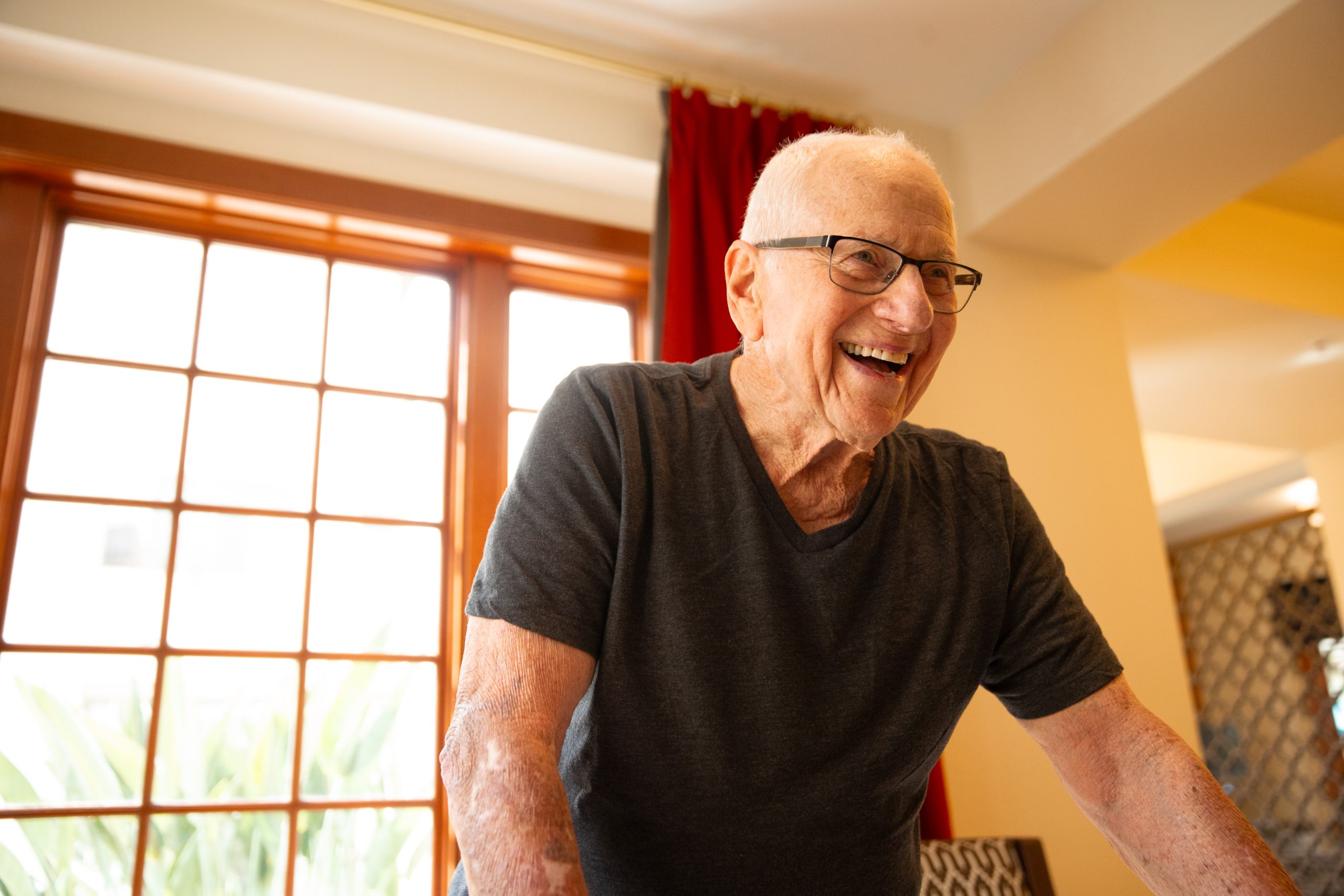 an elderly man smiling with glasses on an exercise bike