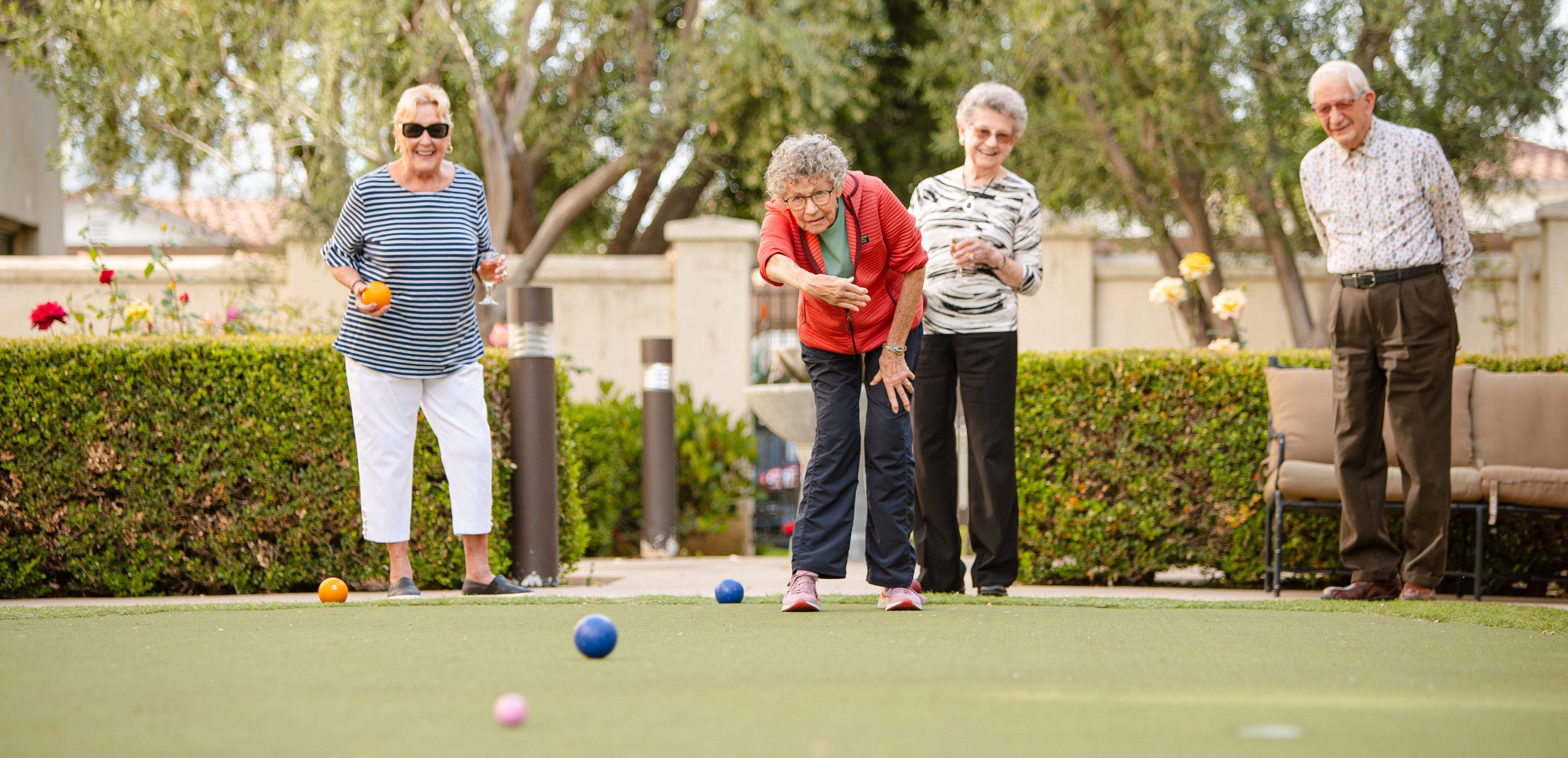 four active elderly friends excited and playing croquet