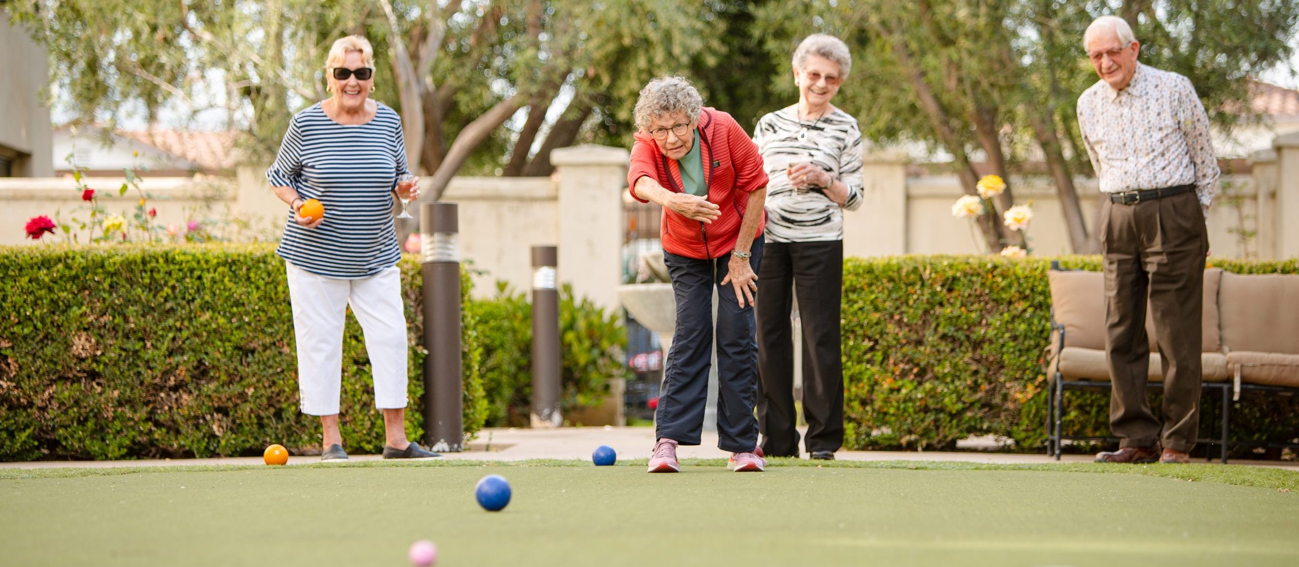 four active elderly friends excited and playing croquet