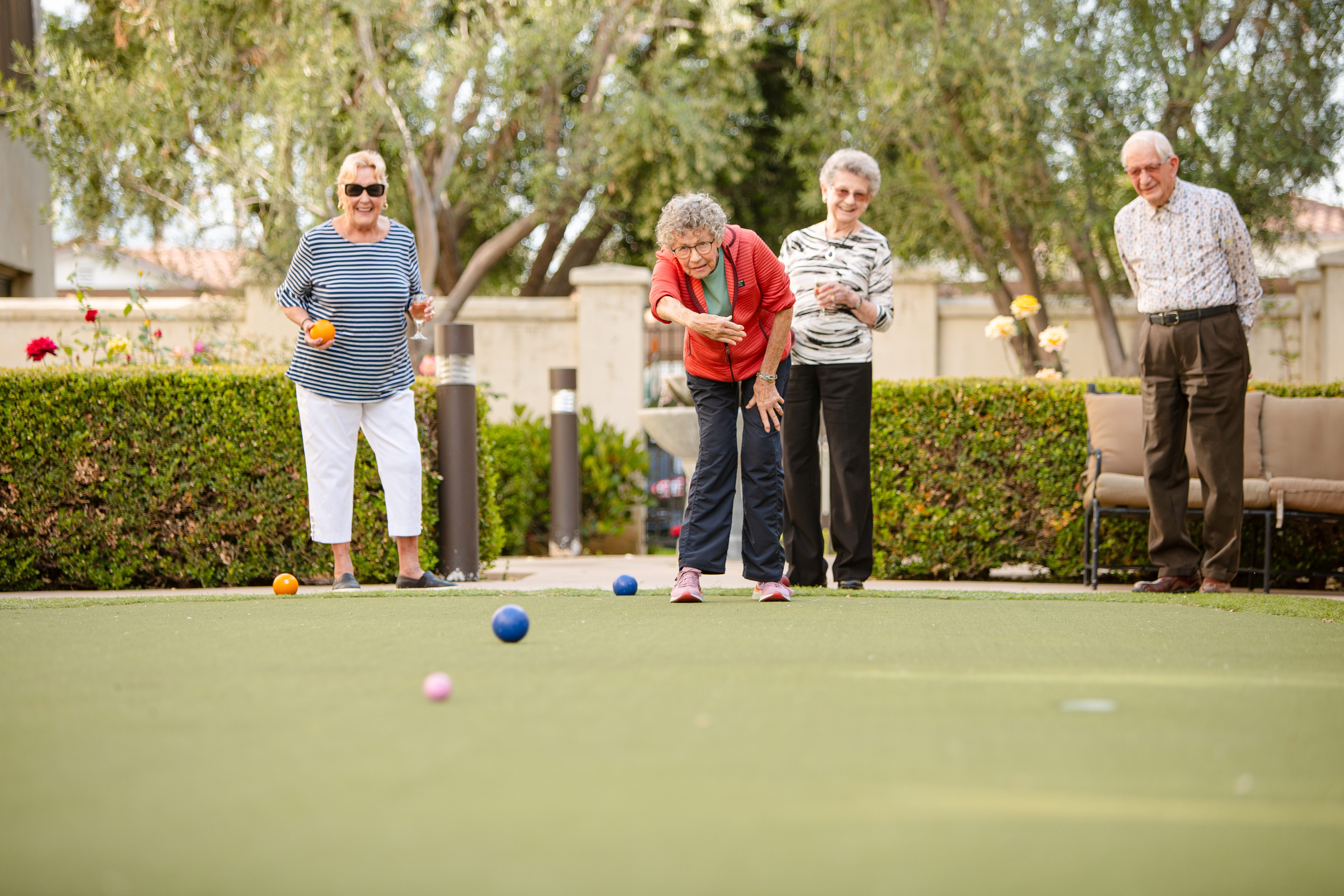 four active elderly friends excited and playing croquet