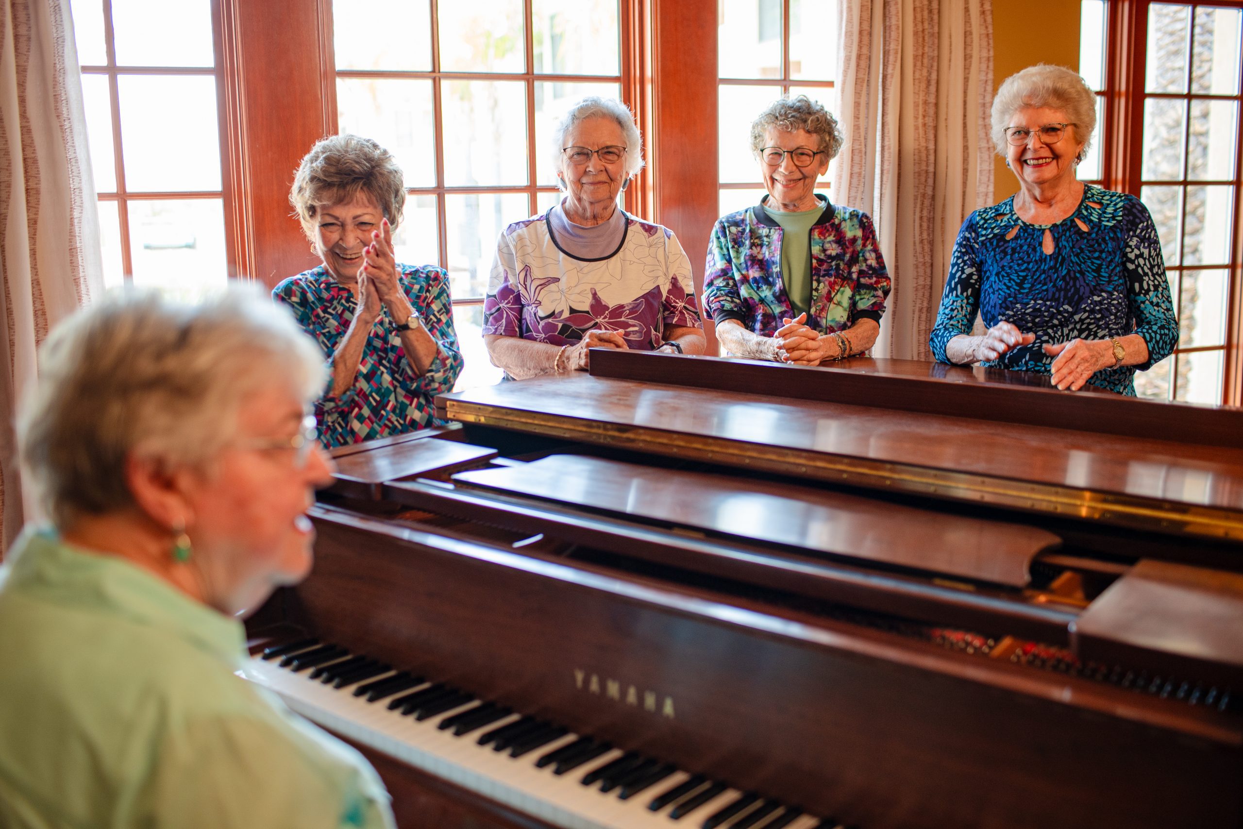 A group of elderly women joyfully playing the piano together.