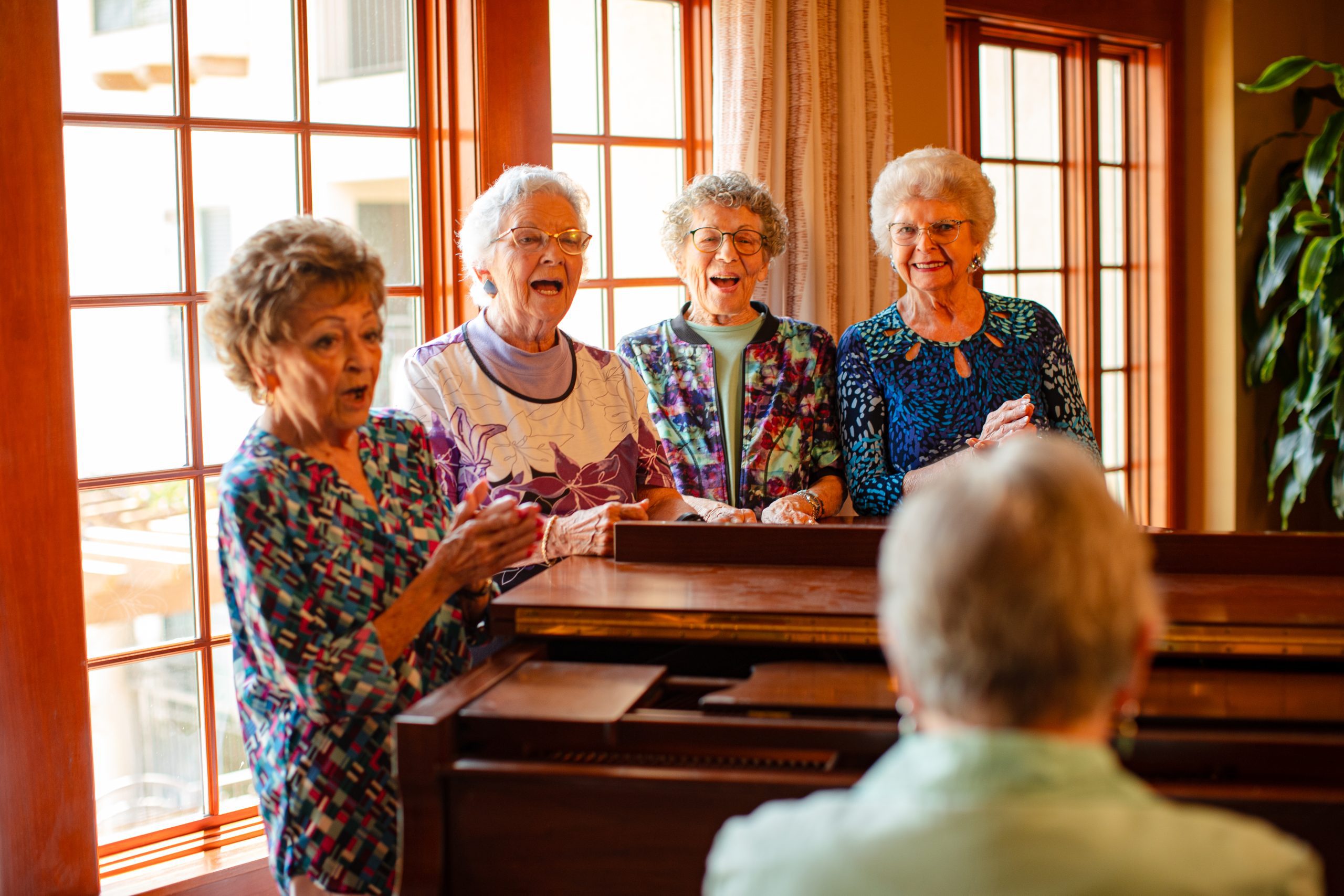 a group of active elderly people singing together next to a piano