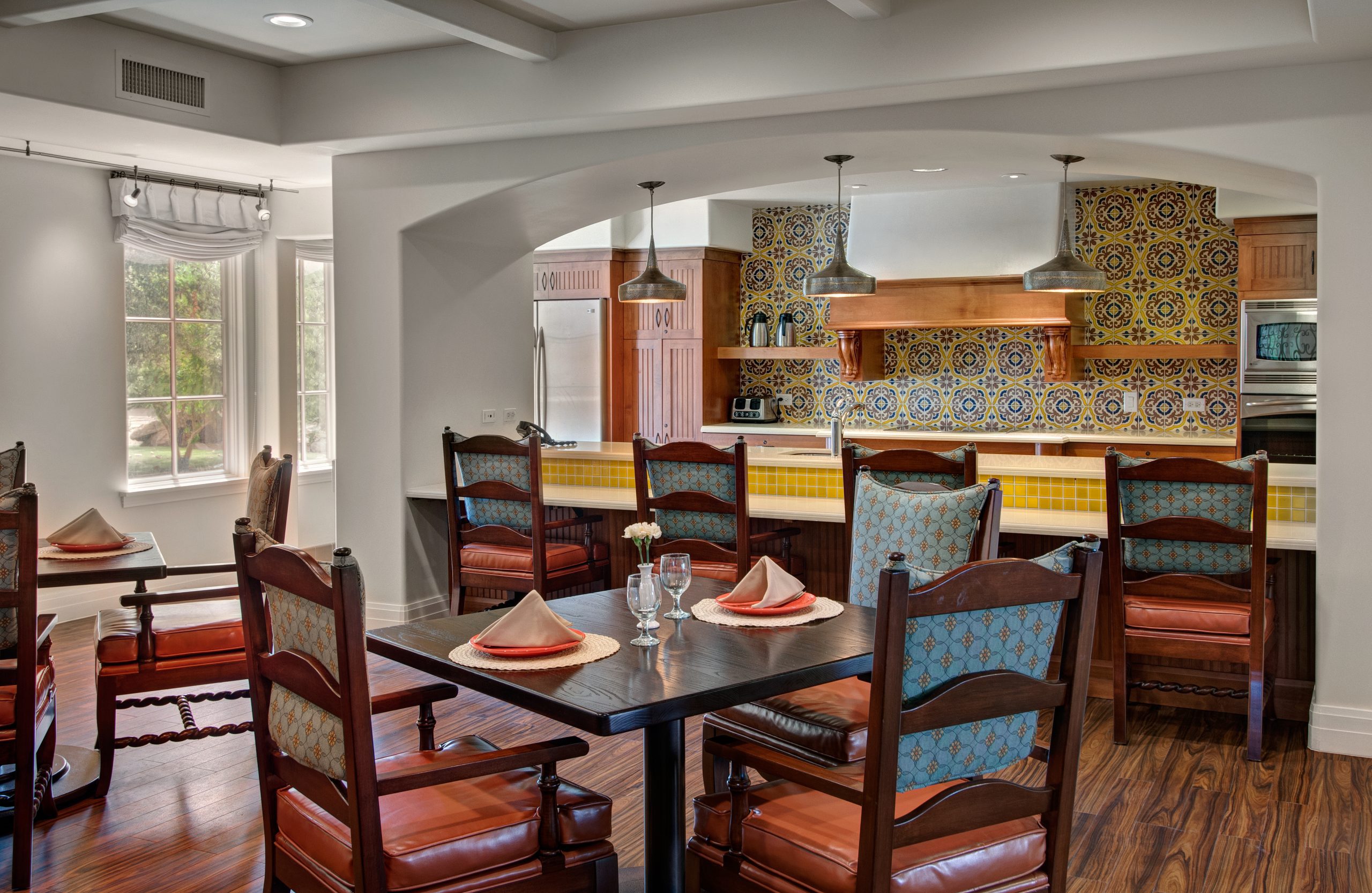 A well-lit kitchen with a wooden dining table and chairs, creating a cozy and inviting atmosphere.