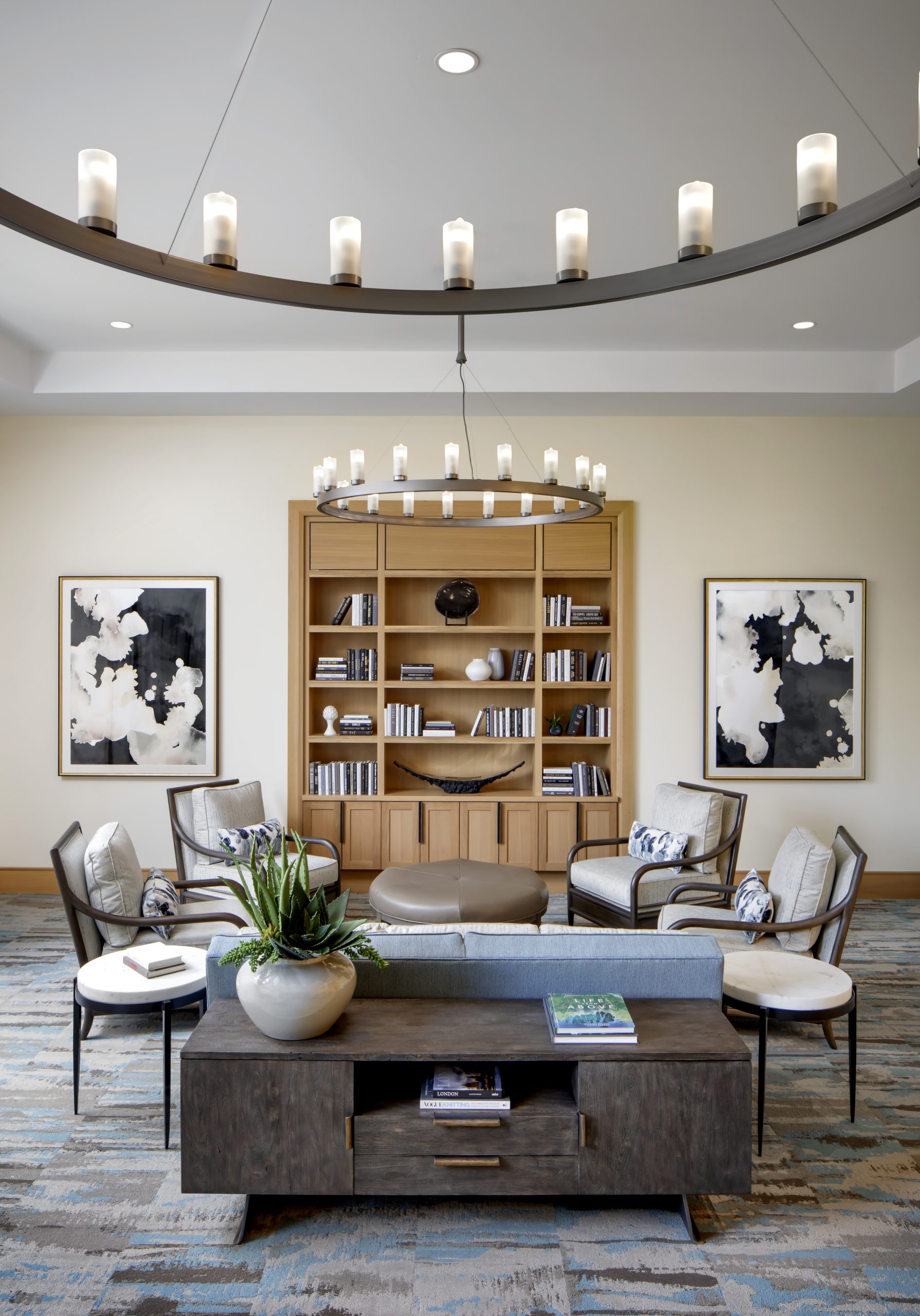 A spacious living room adorned with a sizable round chandelier, illuminating the elegant space.