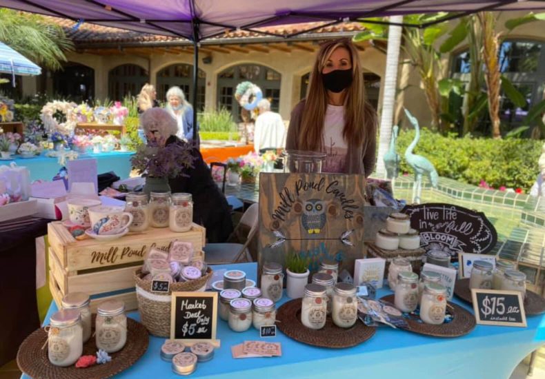 A woman stands behind a table with a variety of items, showcasing her collection or merchandise.