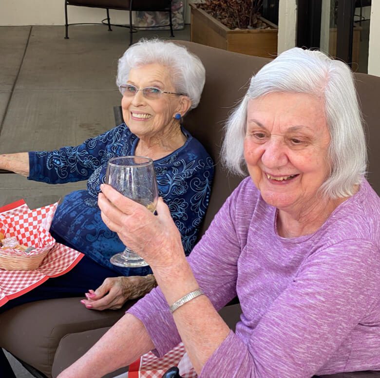 Two women enjoying a conversation on a patio, holding wine glasses and savoring the moment.