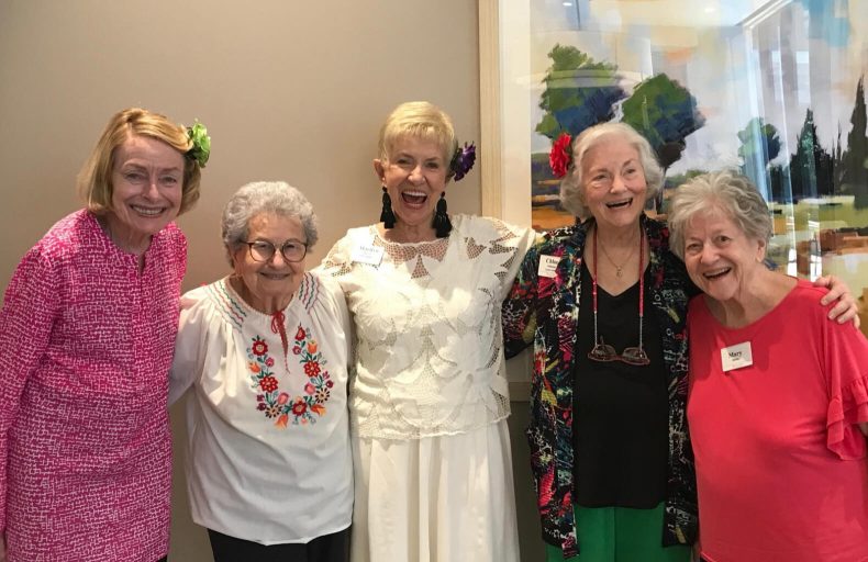 Five older women posing and smiling for a picture, radiating joy and camaraderie.