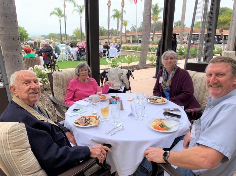 Four people enjoying a meal together at a table, filled with delicious food and engaging in conversation.