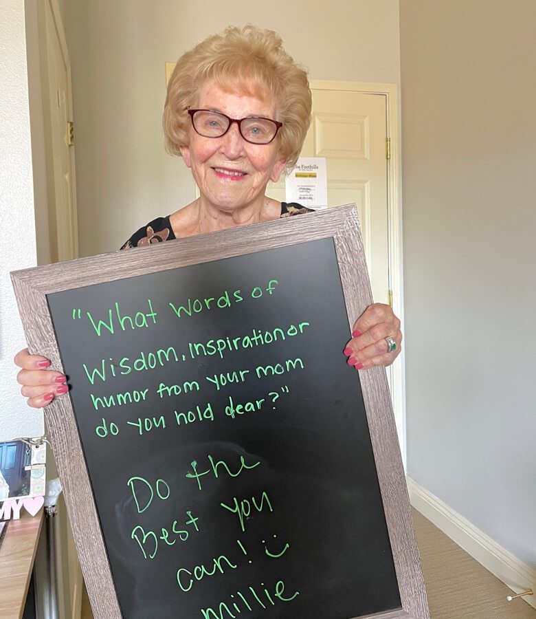 An elderly woman holds a sign, seeking words of wisdom.