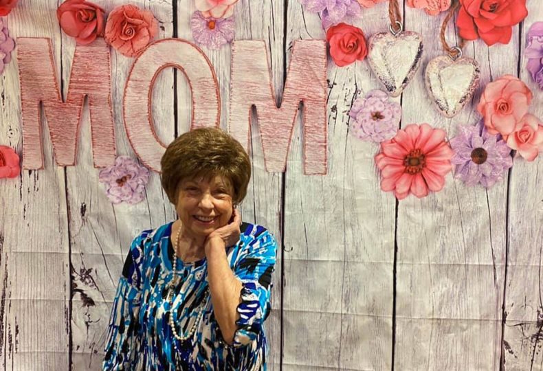 A woman smiling in front of a sign that reads 