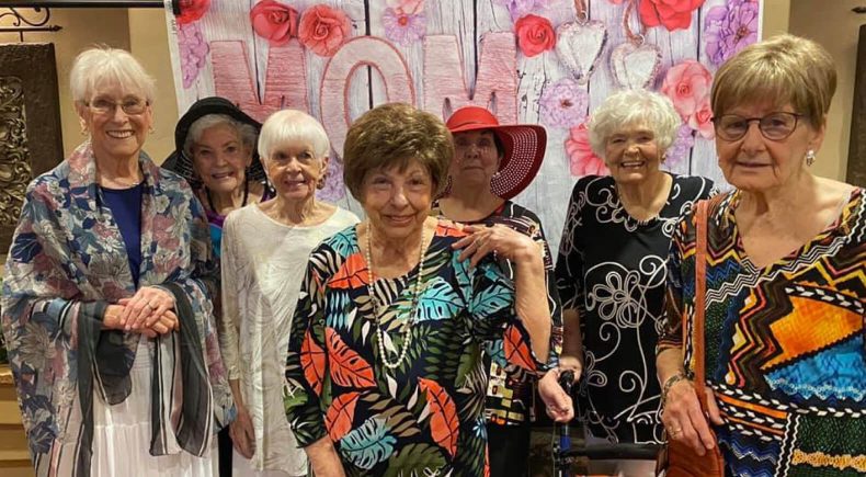 A group of elderly women smiling and posing together for a photograph.