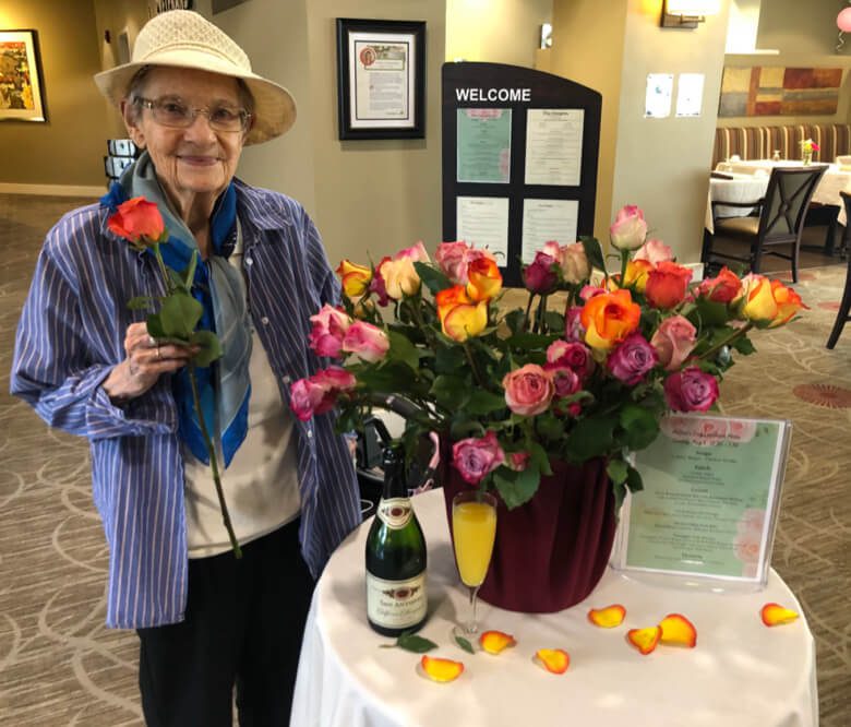 An elderly woman smiling while holding a beautiful bouquet of roses, radiating joy and love.