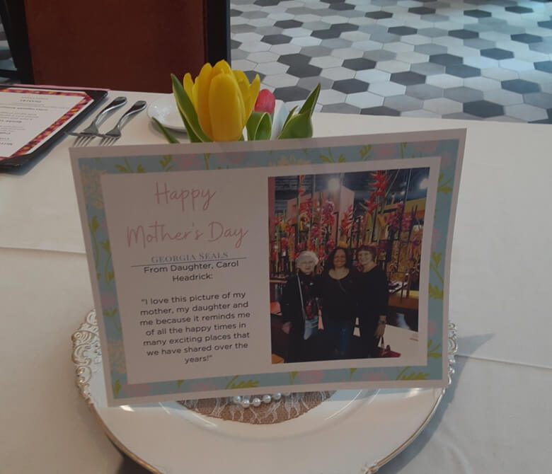 A beautifully arranged table with flowers, candles, and elegant dinnerware for a Mother's Day celebration.