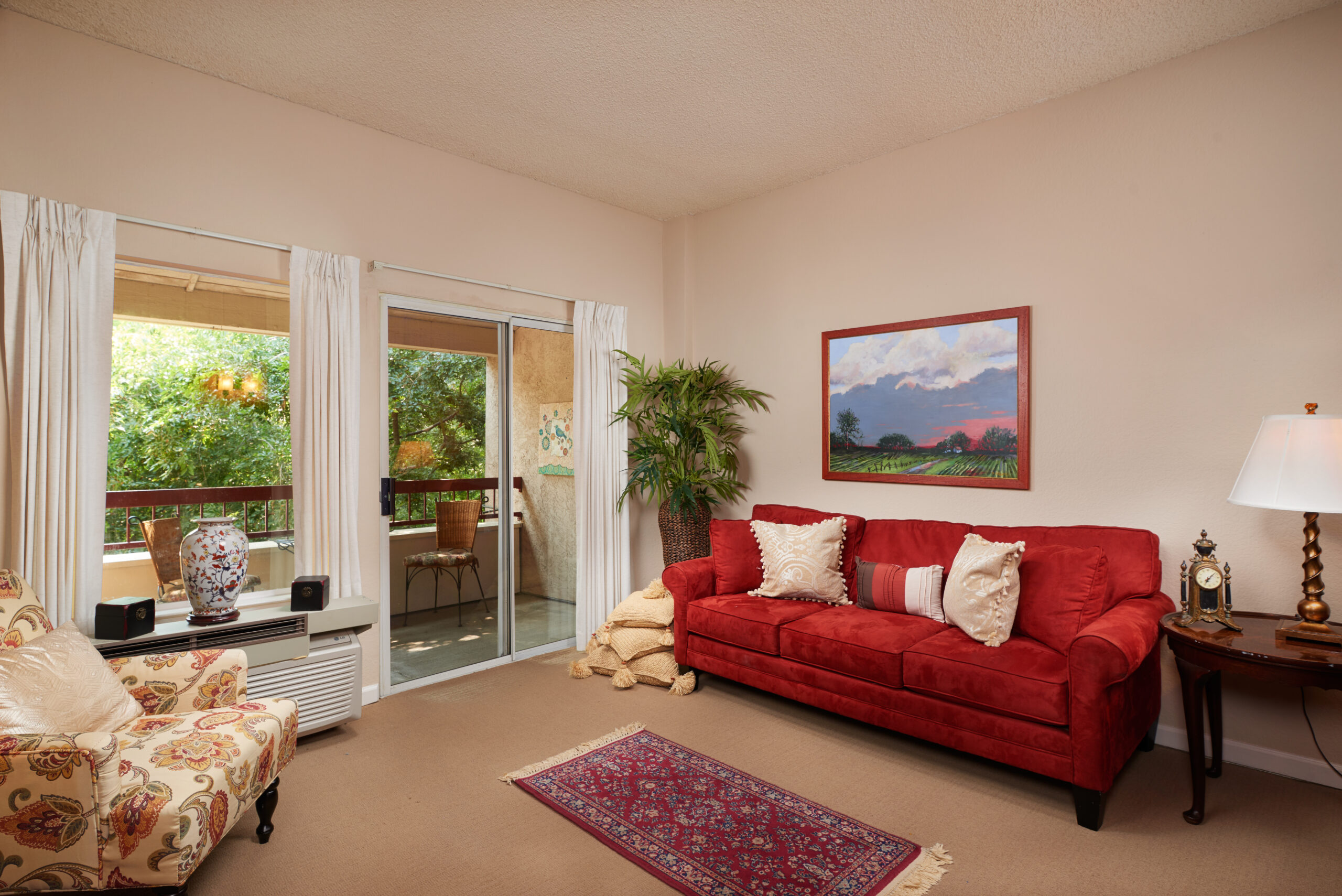 A cozy living room with a vibrant red couch and a captivating painting on the wall.