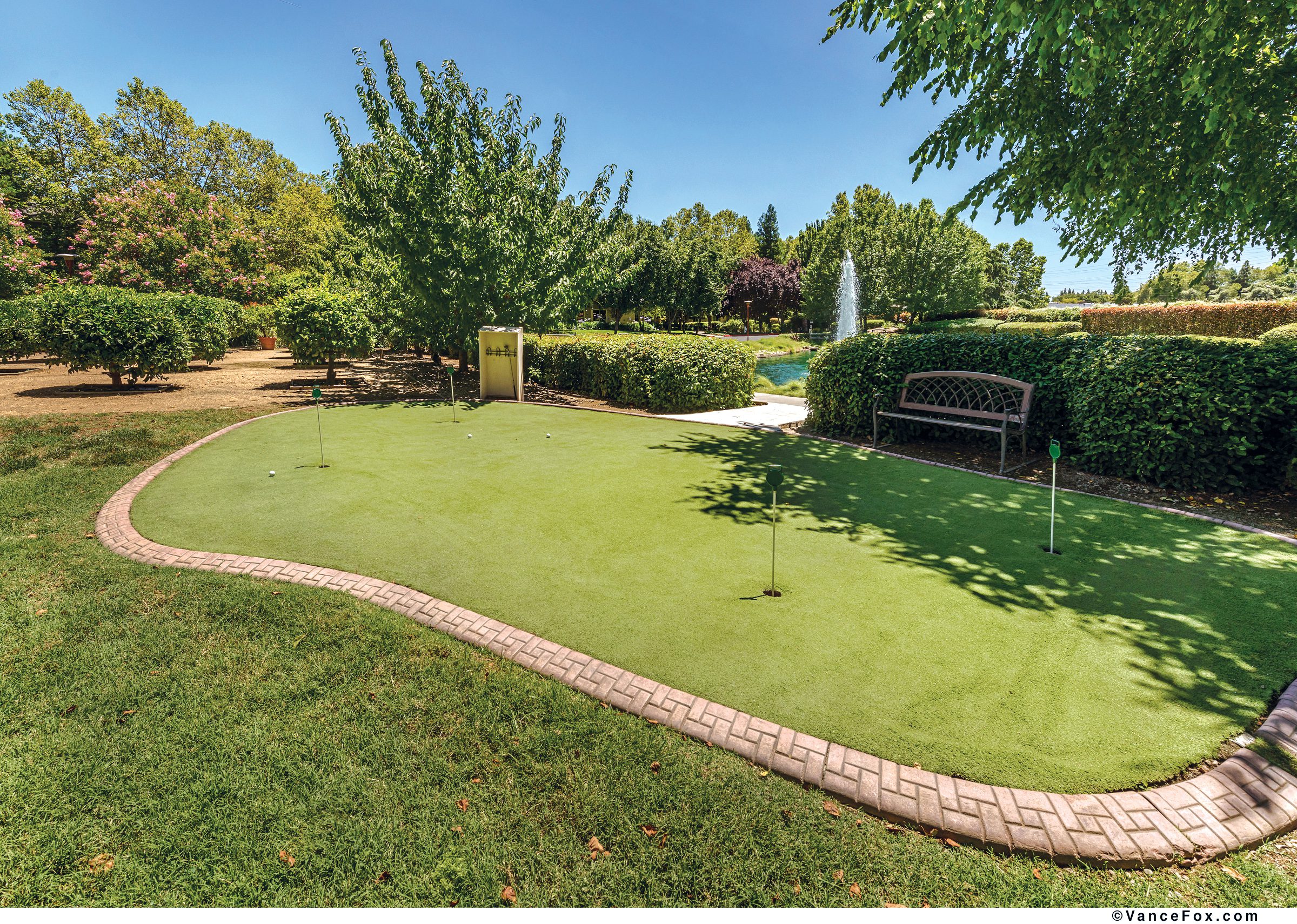 A backyard putting green with a serene fountain, perfect for practicing your golf skills.