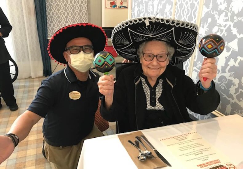 An elderly woman wearing a Mexican hat and glasses, radiating warmth and wisdom.