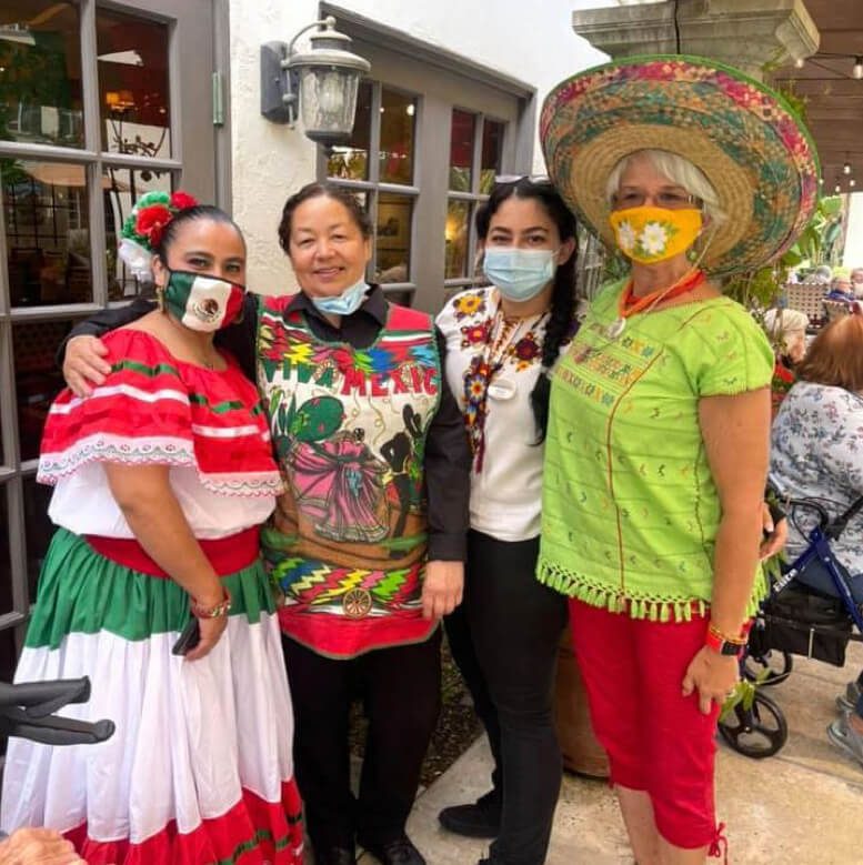 Four women in colorful Mexican costumes posing for a photo, showcasing their vibrant cultural attire.