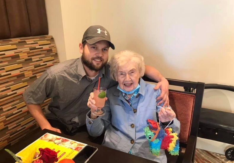 A man and an elderly woman enjoying coffee together at a table.