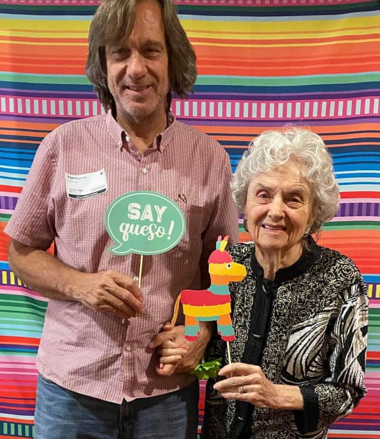 A couple of people posing before a vibrant cinco de mayo backdrop.