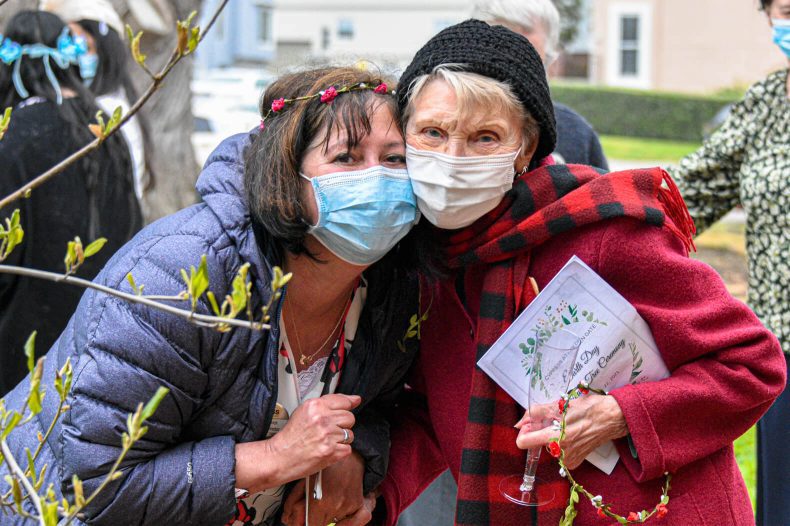 Two women wearing face masks and holding a book, practicing safety measures during the pandemic.