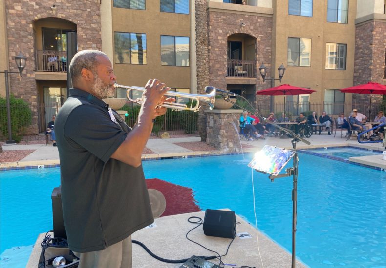 A man playing the trumpet by the poolside, creating melodious tunes amidst a serene setting.