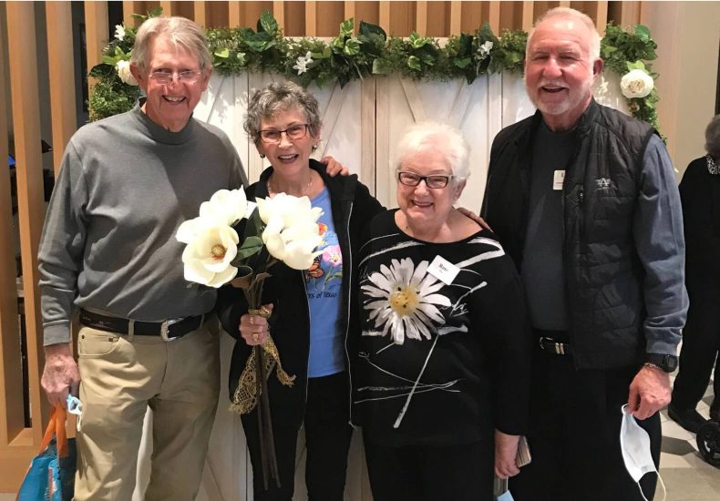 Three elderly individuals and a woman holding flowers.